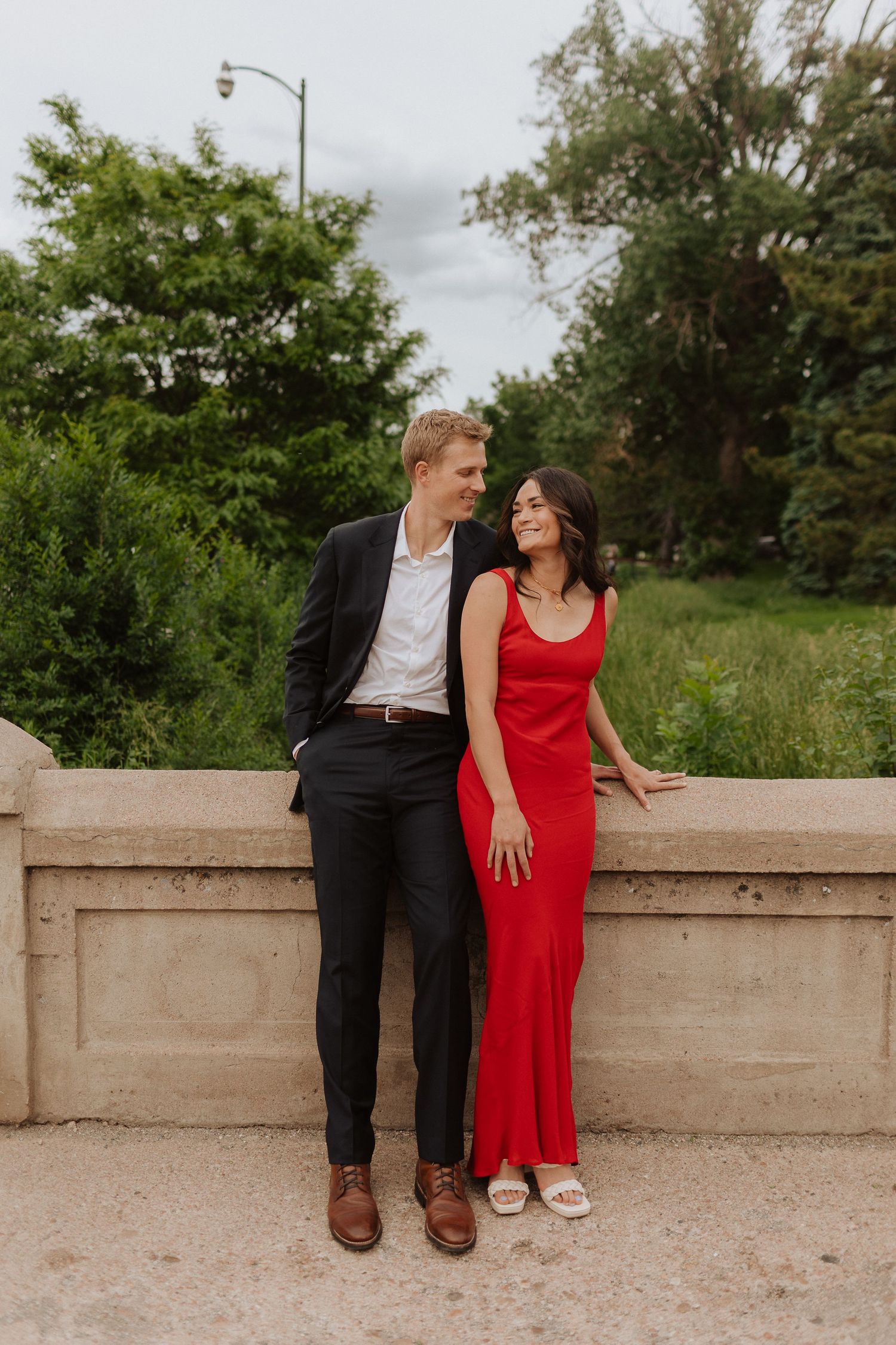 Couple sitting on concrete wall sharing intimate moments in outdoor setting.