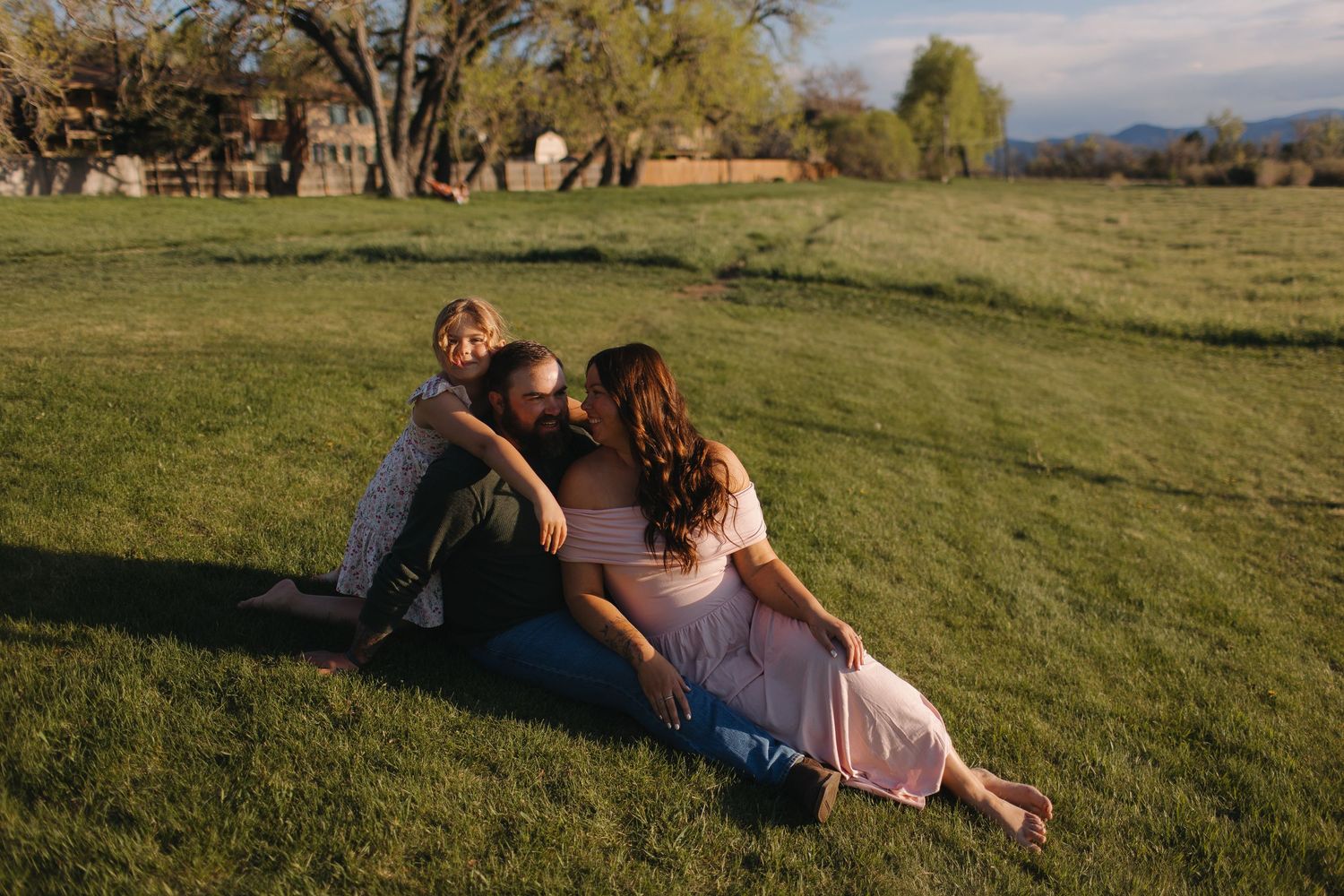 Intimate moment between couple relaxing on grassy hillside at sunset.