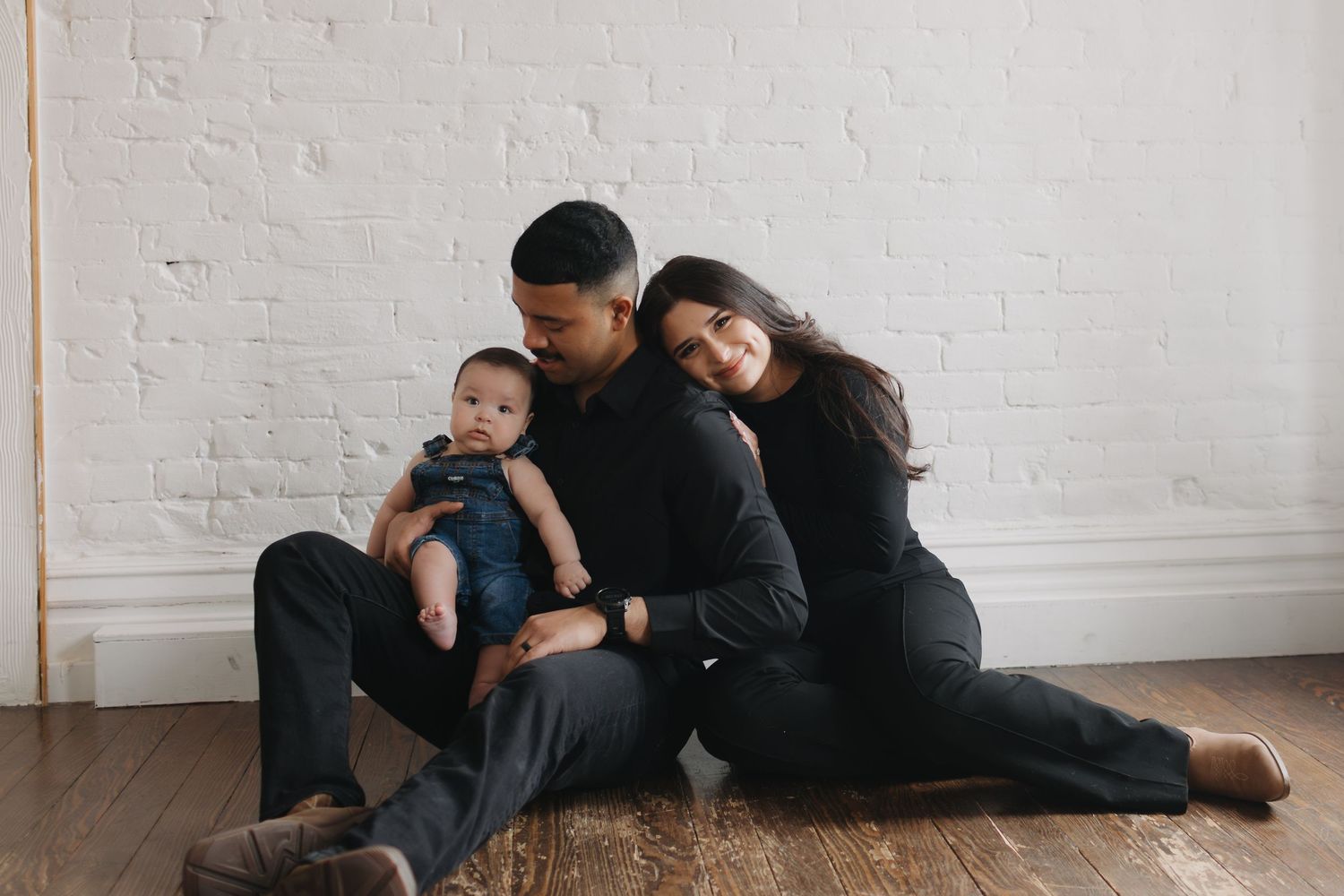 A candid indoor photo session showing tender family moments on a white floor.