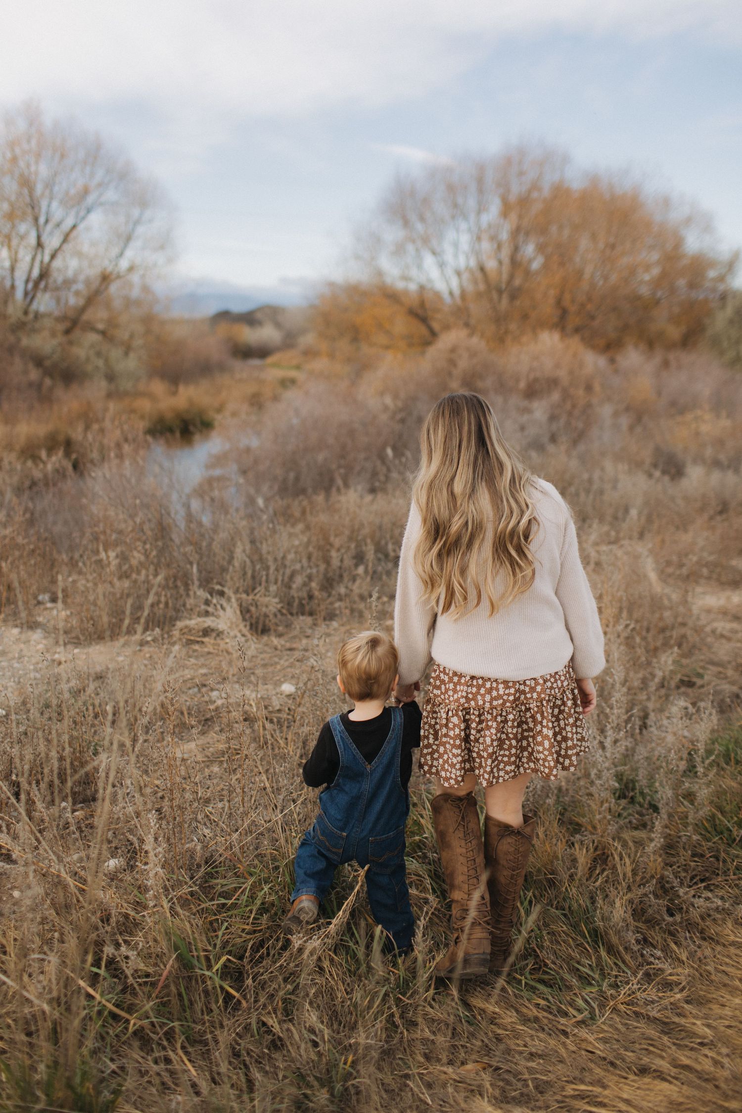Autumn outdoor photoshoot showing figures walking through tall dried grass.
