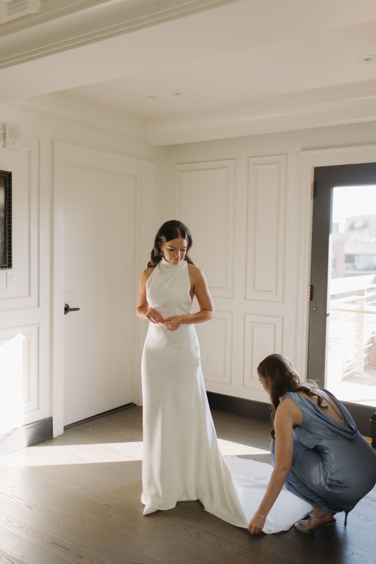 Wedding dress preparation and styling in bright white modern interior space.