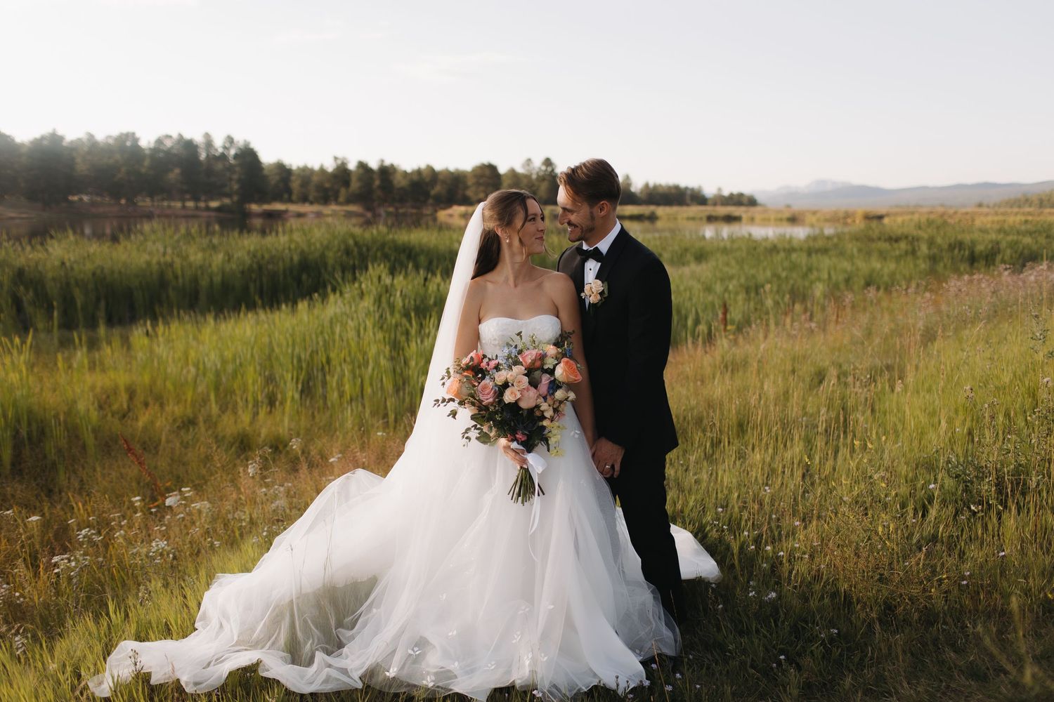 Wedding couple sitting together in a scenic mountain meadow during golden hour.
