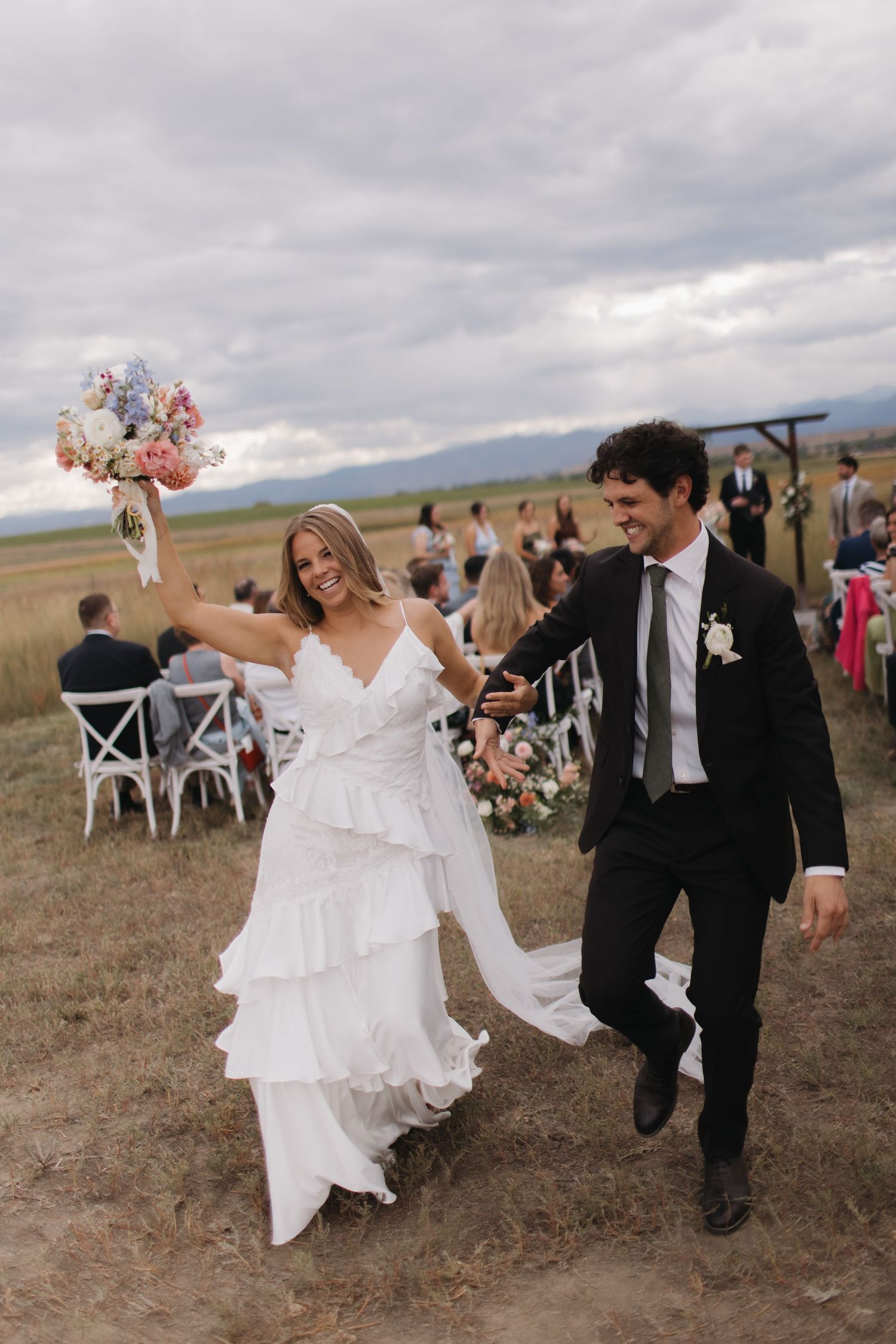 Wedding party celebrating and walking together across an open field.