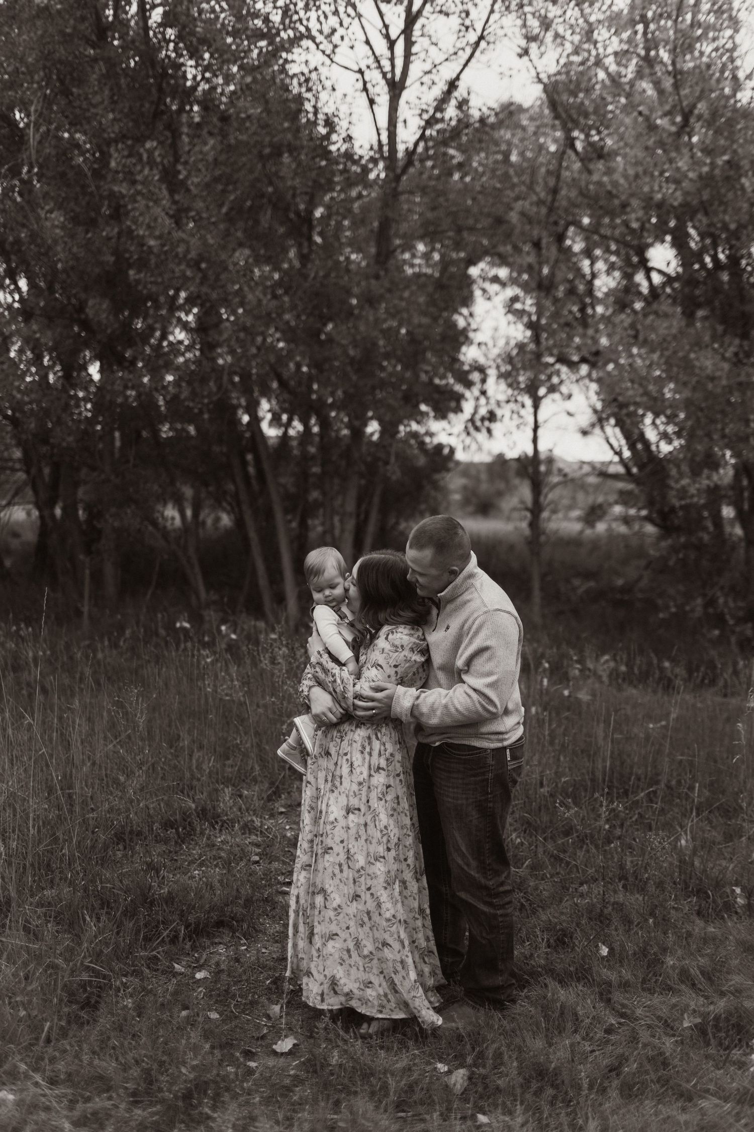 Black and white portrait of a couple sharing intimate moments in a natural outdoor setting.