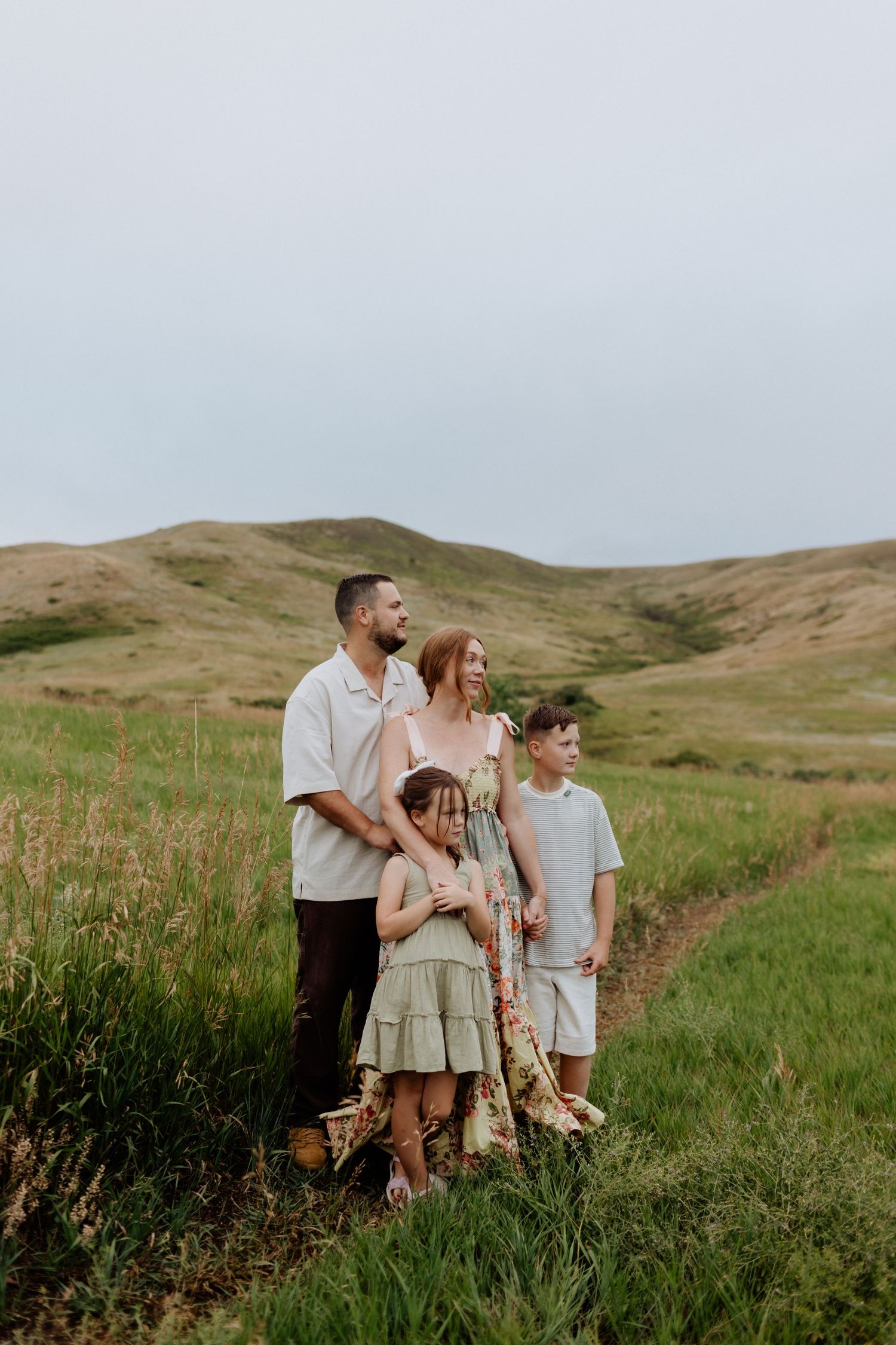 Family portrait session in rolling hills with golden grass and natural lighting.