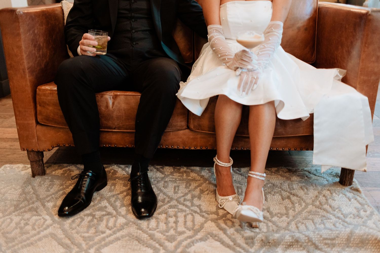 Close-up details of wedding couple's feet and formal attire on patterned carpet.