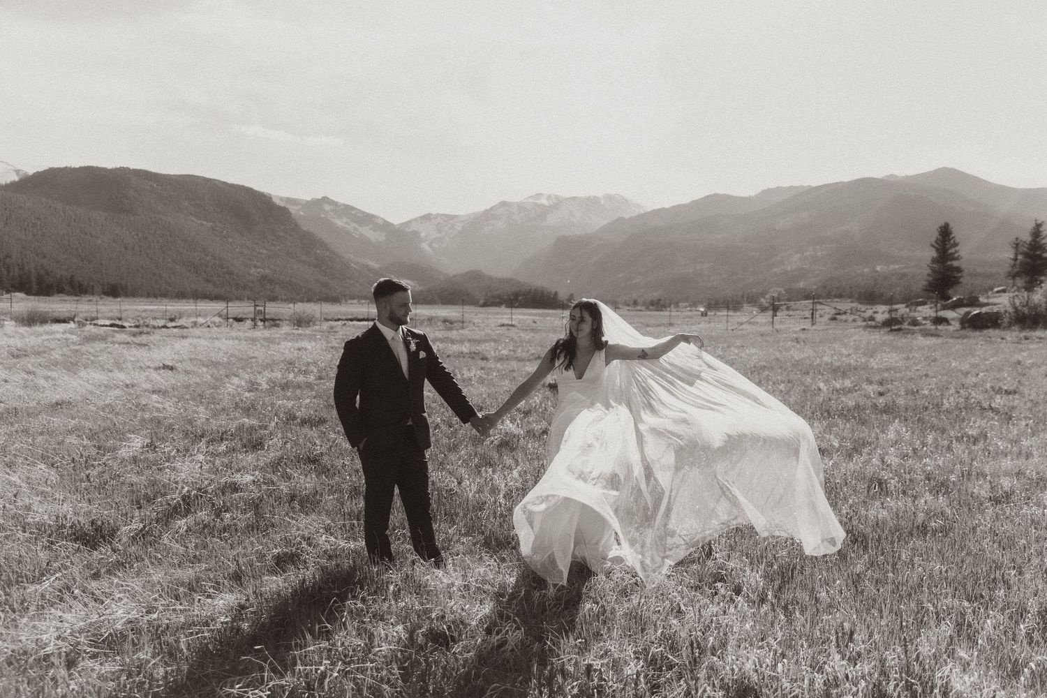 Dramatic black and white wedding photos in an open mountain meadow with flowing veil.
