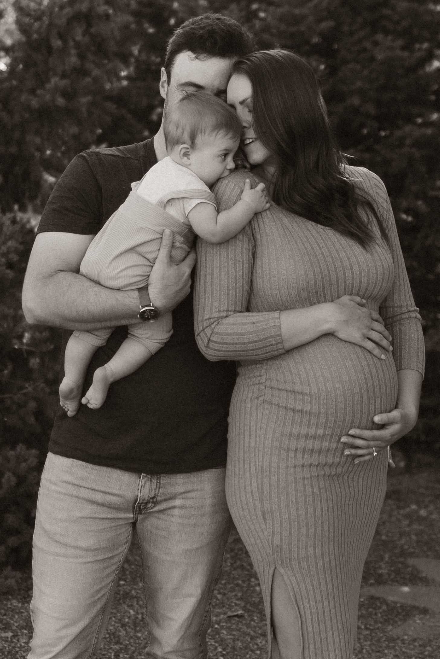 Intimate family moment captured in black and white showing expectant mother in ribbed dress.