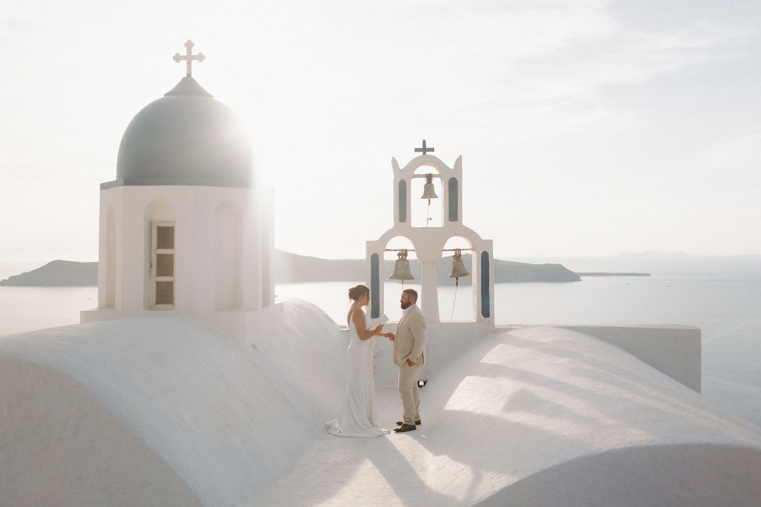 White church domes and architecture against bright sky in Santorini, Greece.
