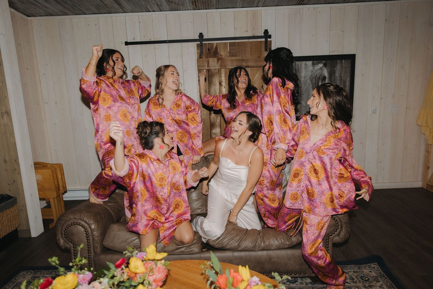 Wedding party members in pink floral dresses celebrate during reception festivities.