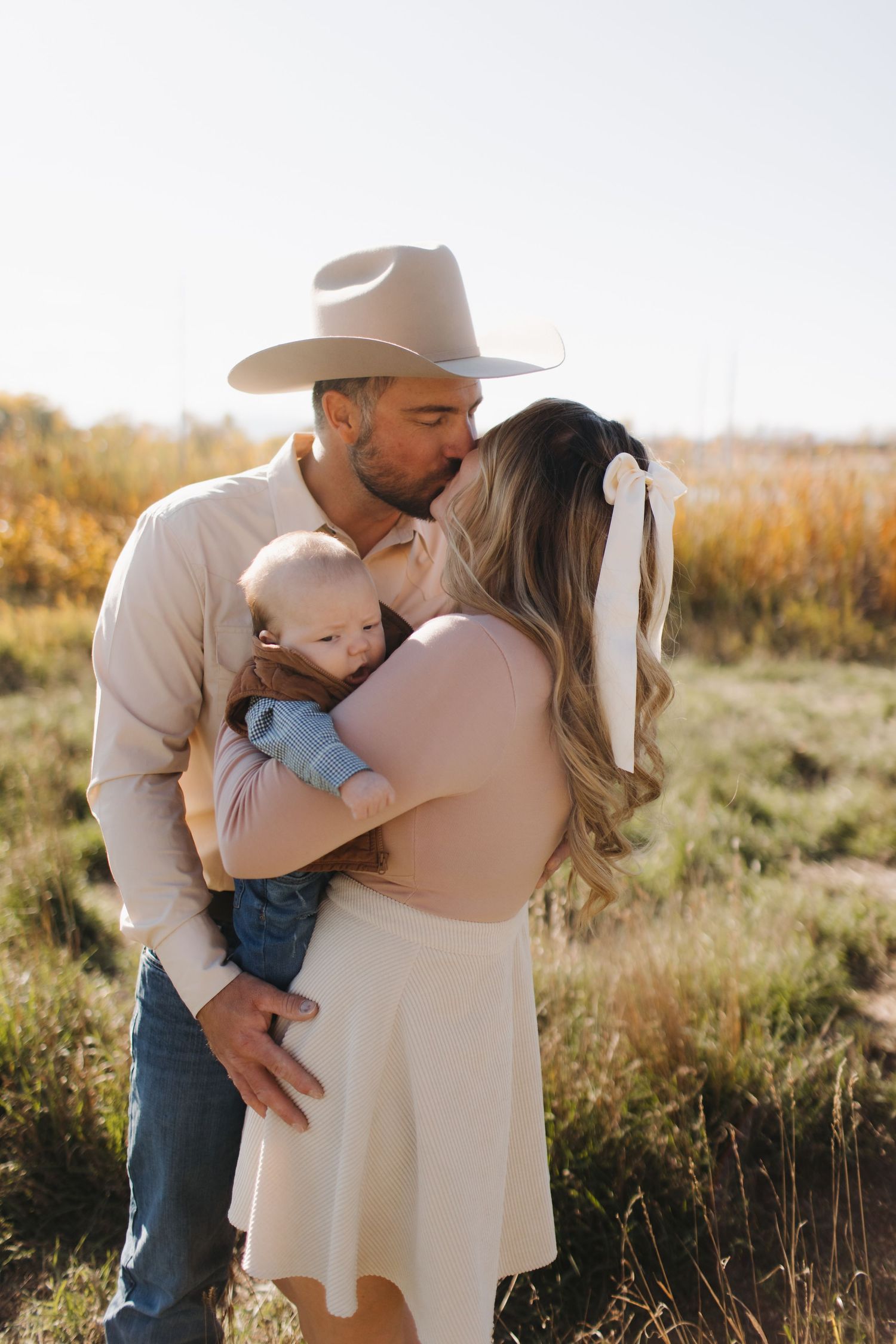 A tender family moment captured in golden light with a baby in a rustic outdoor setting.