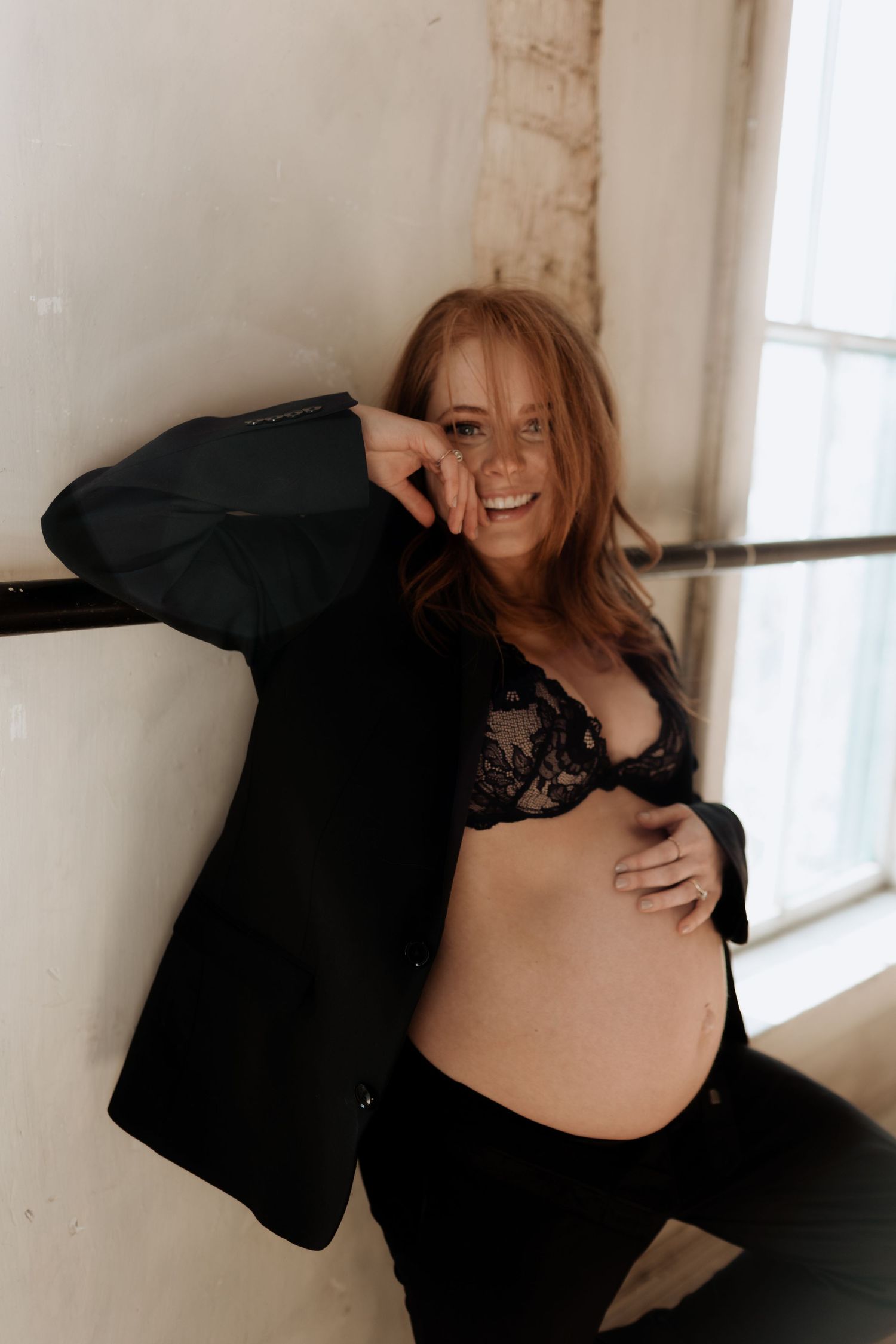 A joyful maternity photo shoot in a rustic room with natural window light.