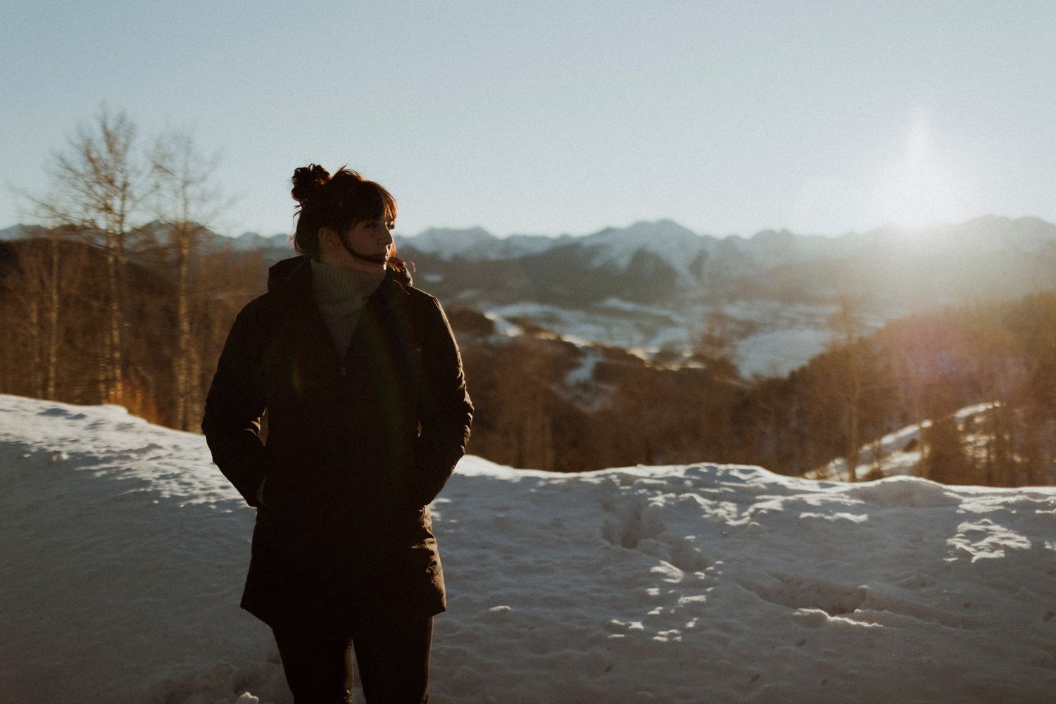 Silhouette of person against snowy mountain landscape at sunset.