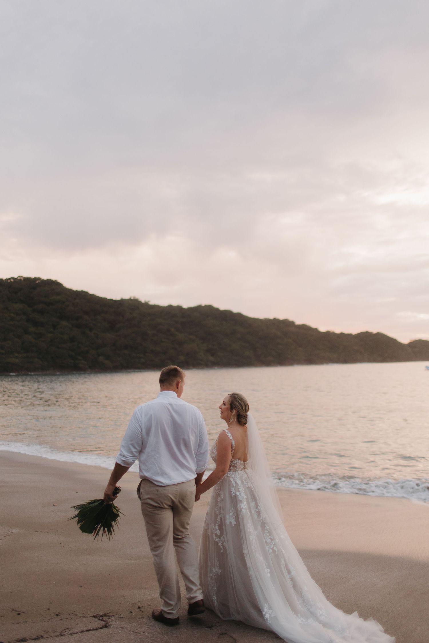 Beachside wedding portraits at sunset with waves and coastline in background.