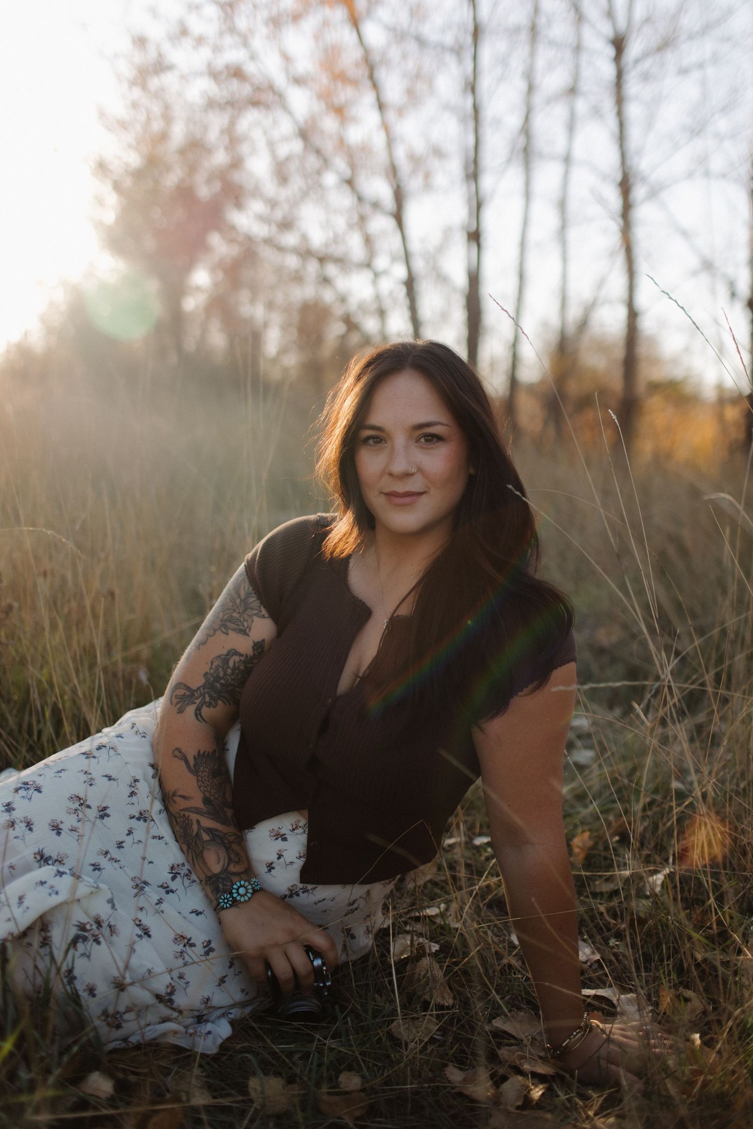 Outdoor portrait session featuring a floral dress against natural grass and woodland backdrop.