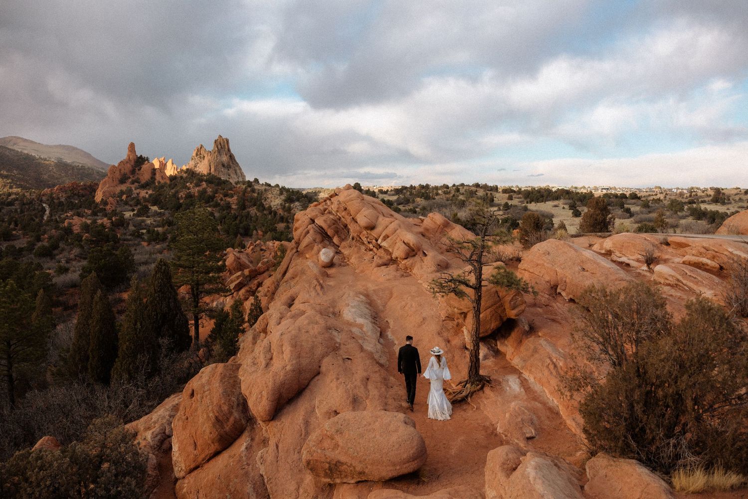 Red rock formations in a desert landscape under cloudy skies during golden hour.