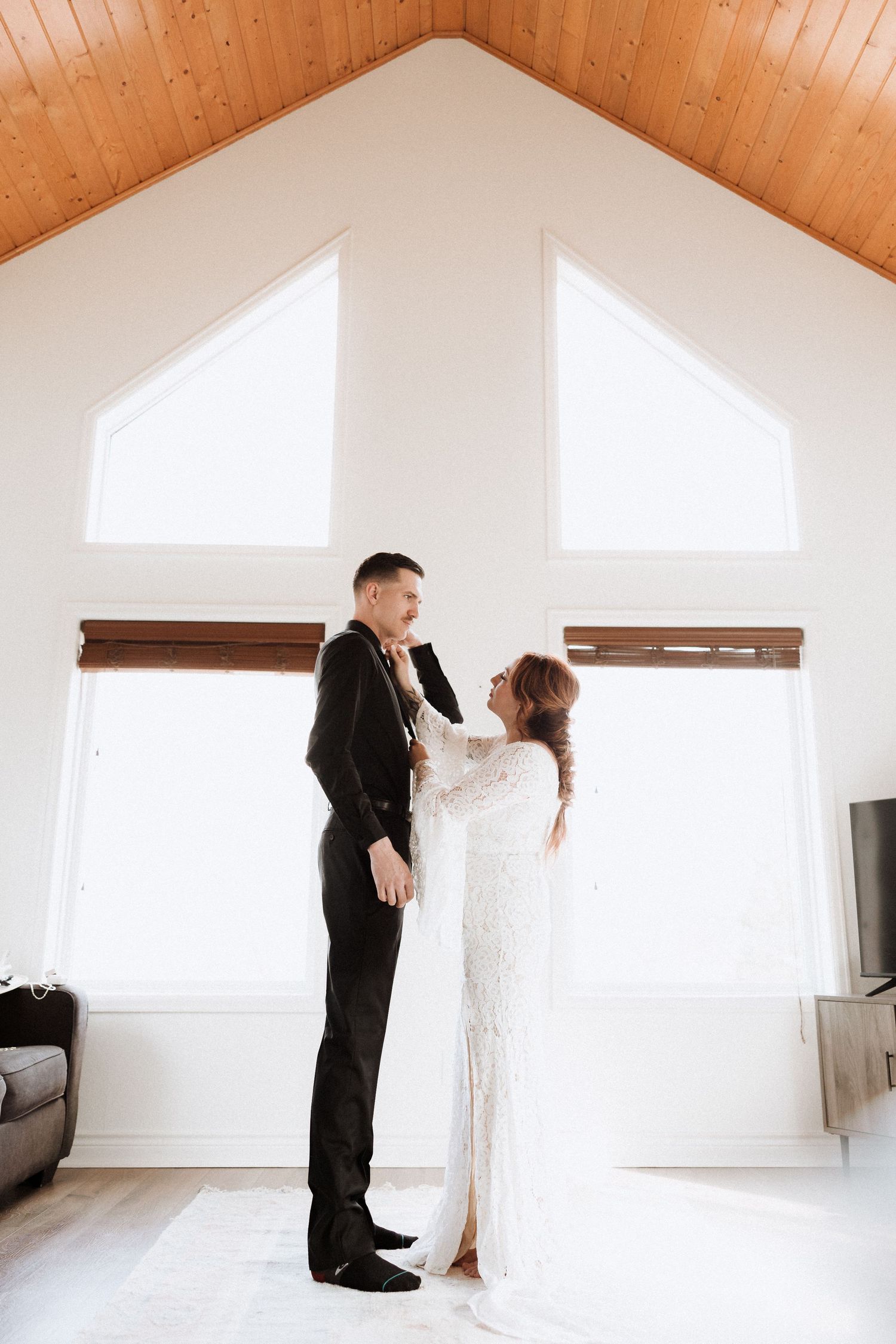 Minimalist wedding photos in a bright white room with wooden ceiling beams.