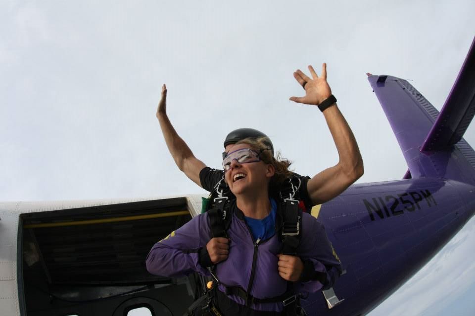 A skydiver shows excitement while falling through the sky with arms raised.