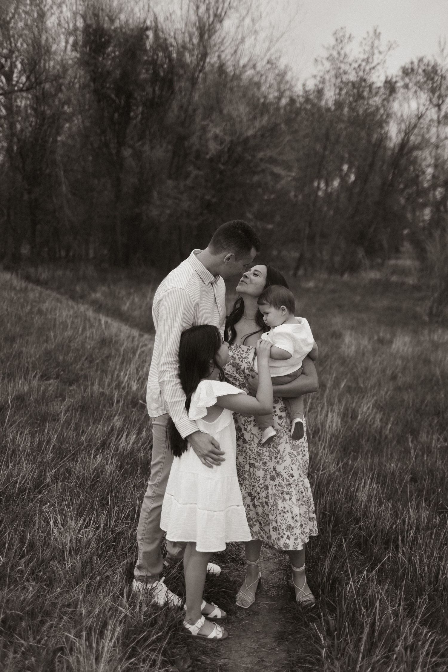 Candid black and white family moments captured in a natural field setting.
