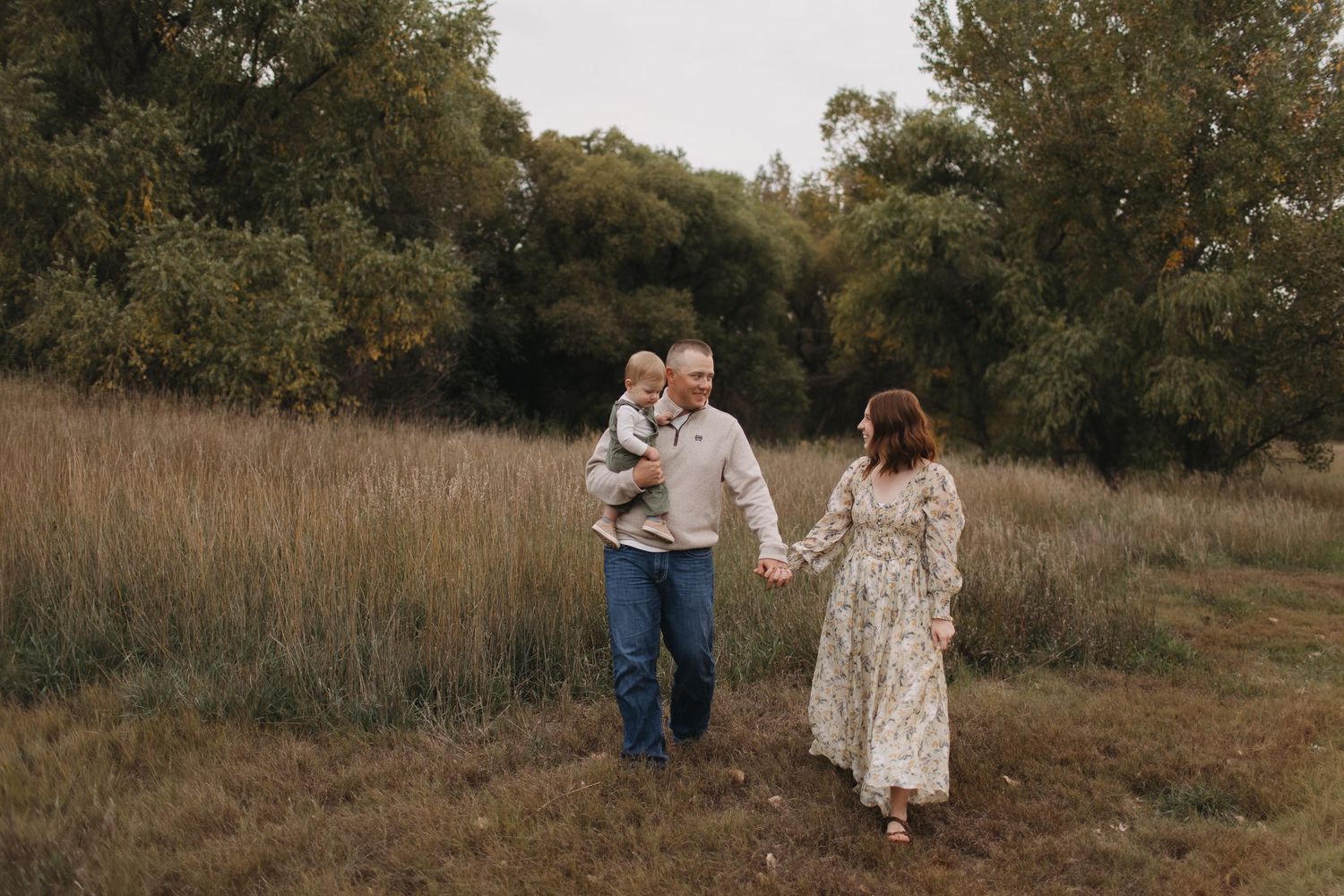 Couple embracing in a rustic field during golden hour photography session.