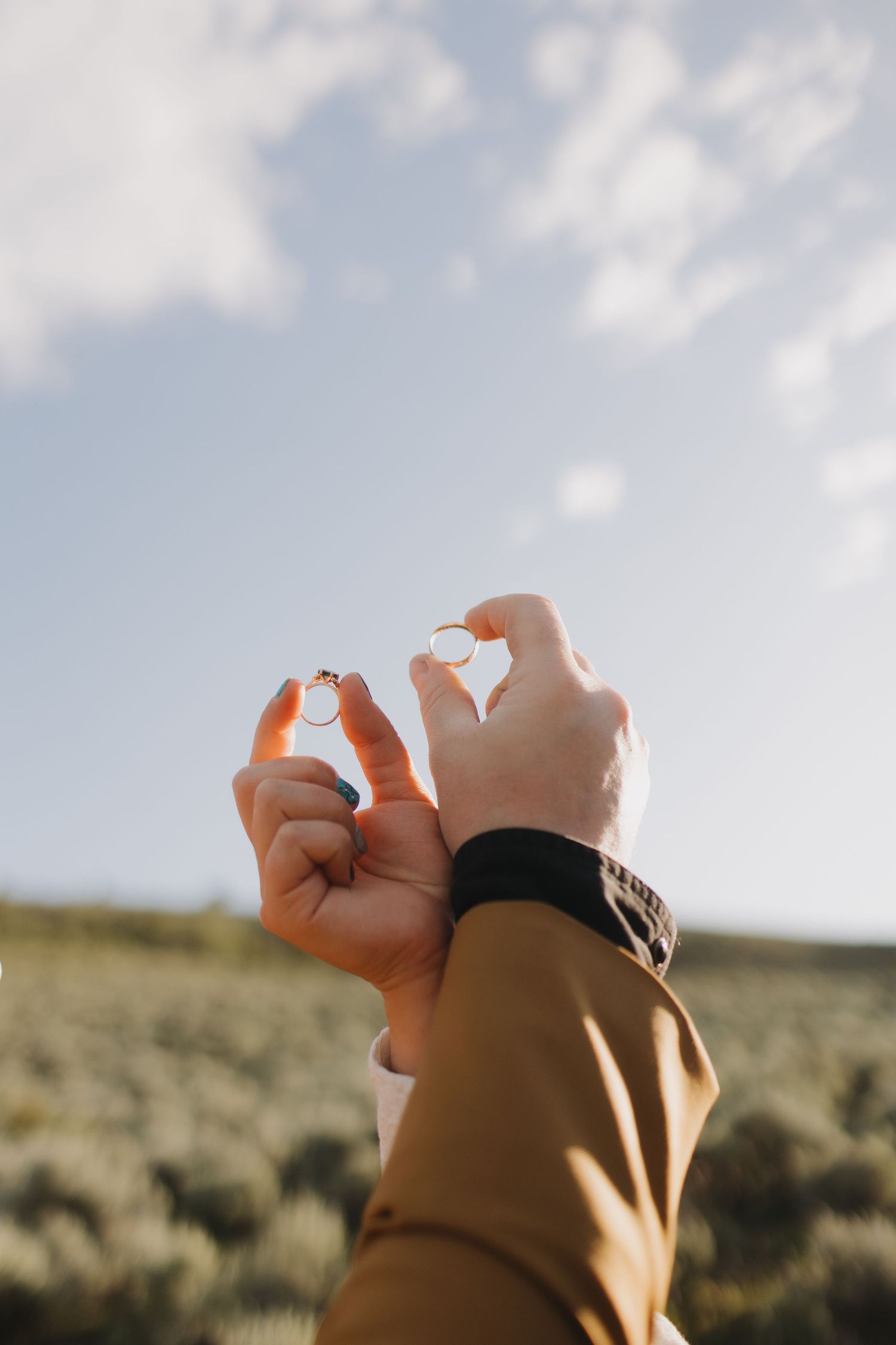 Hands forming a heart shape against a bright blue sky and desert landscape.