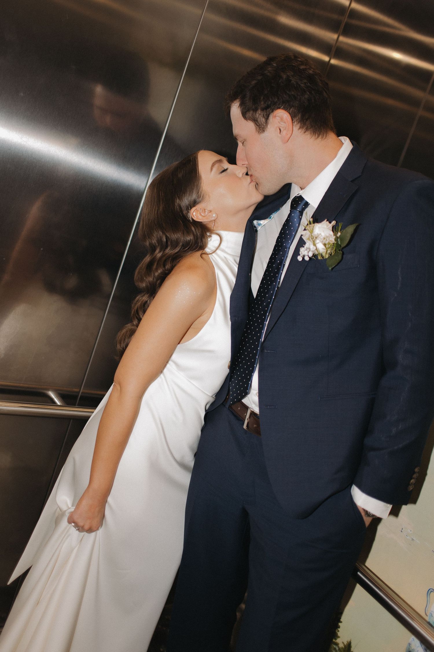 Intimate wedding couple moments captured in modern elevator with metallic walls.