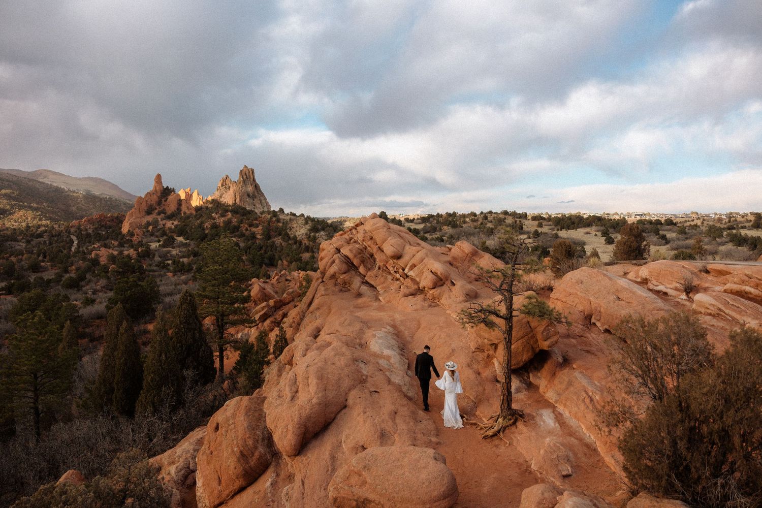 Red rock formations in a desert landscape under dramatic cloudy skies.