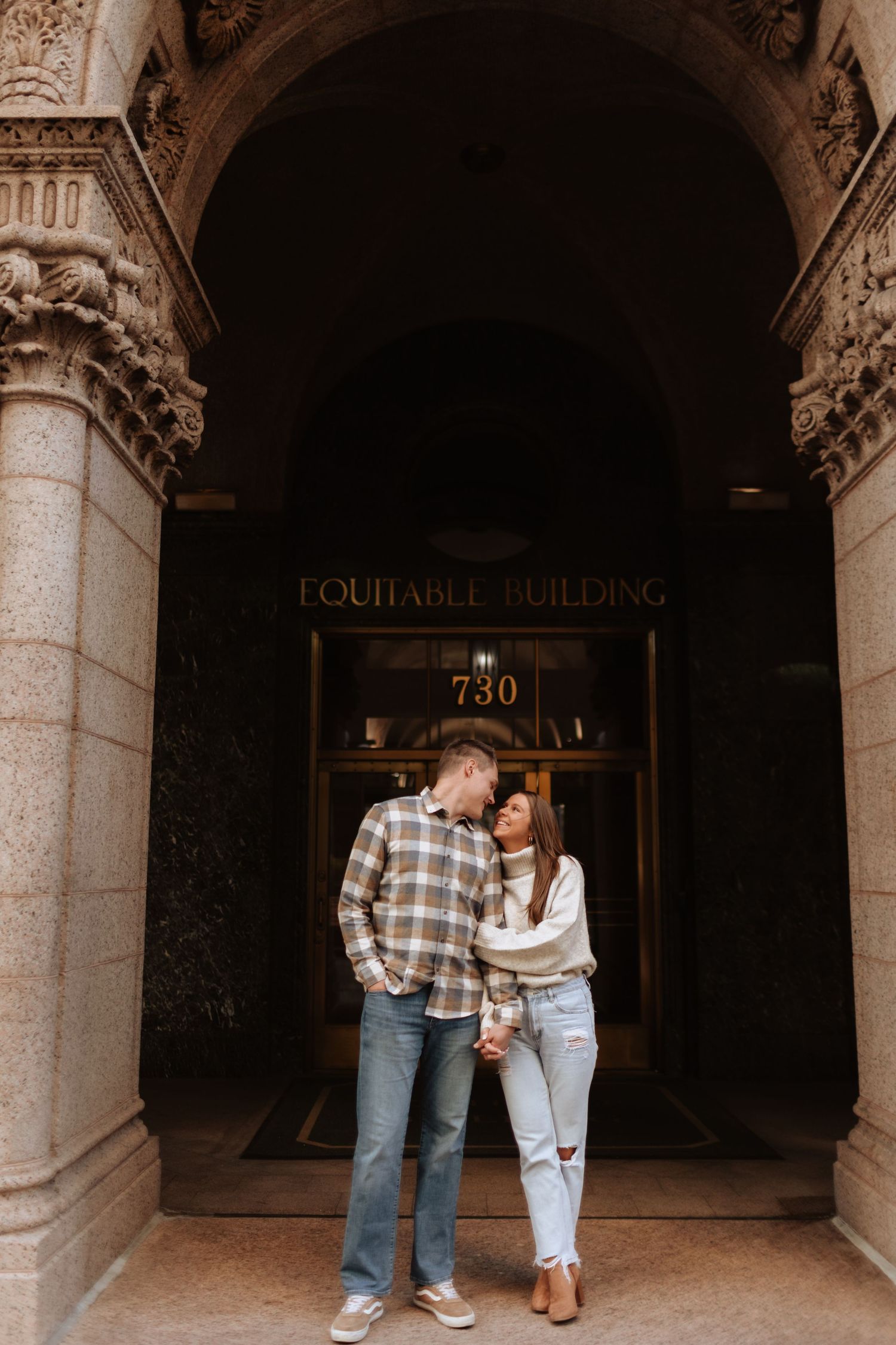 Romantic couple sharing intimate moments in an archway with classic architectural columns.