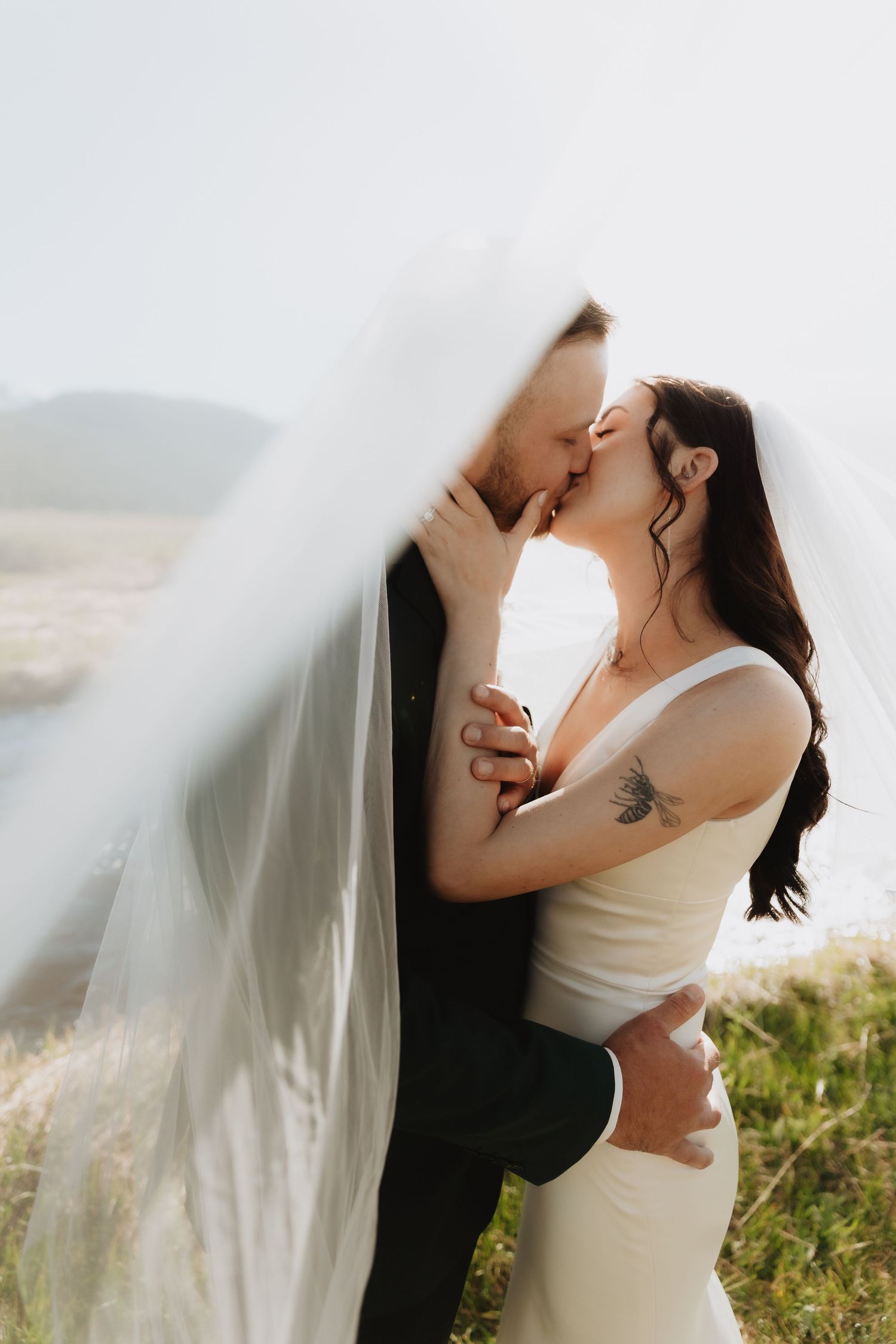 Intimate wedding portraits with flowing veil against natural outdoor backdrop.