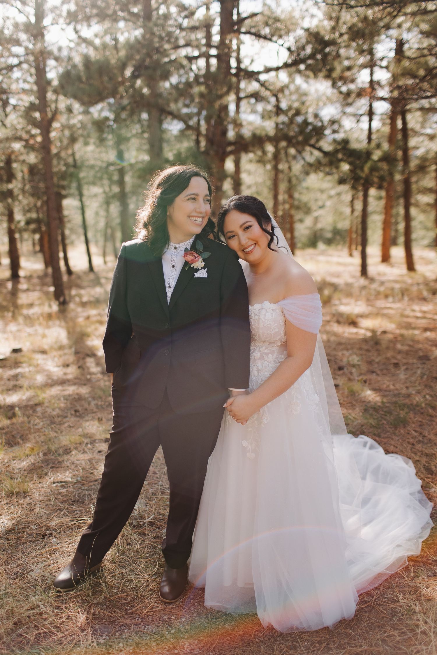 A romantic wedding photo session in a pine forest with a flowing white dress and dark suit.