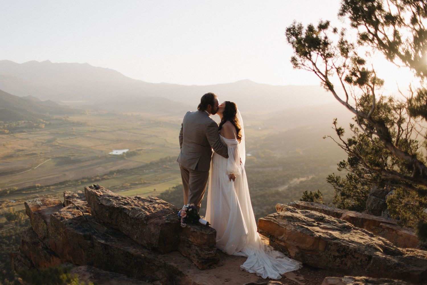 Sunset wedding portraits on mountain overlook with dramatic valley views.