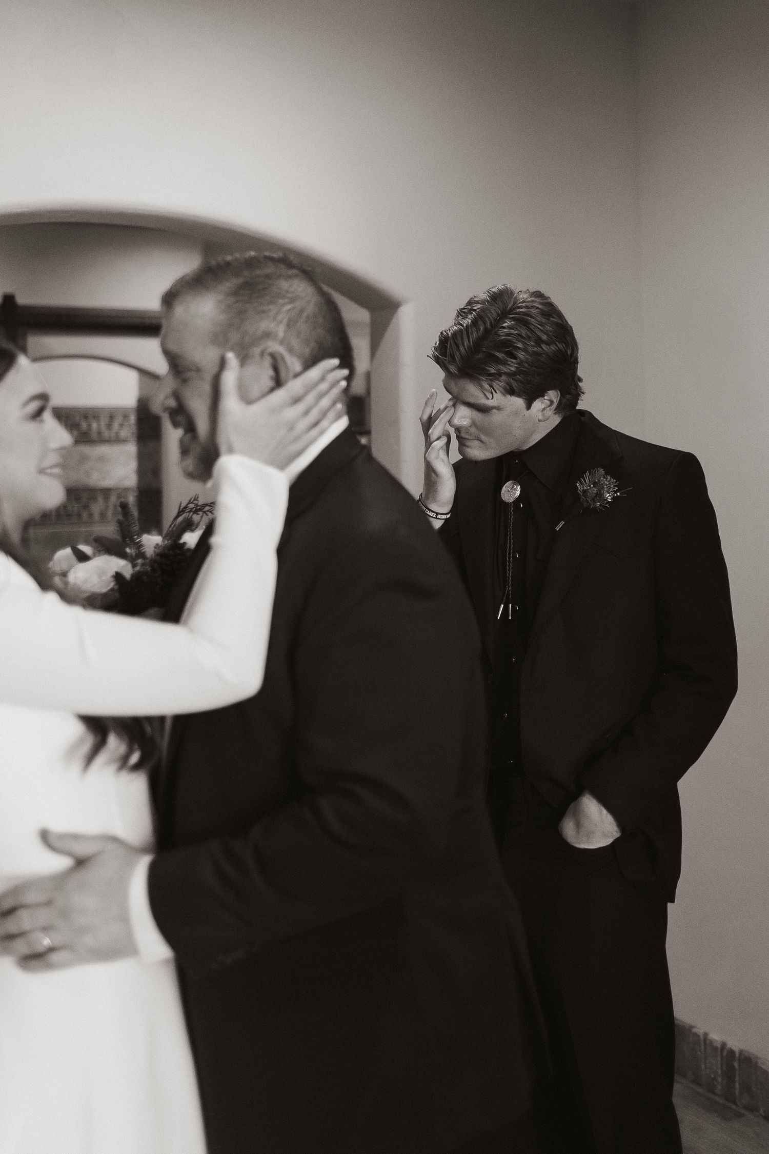 An emotional black and white moment captured during a wedding ceremony indoors.