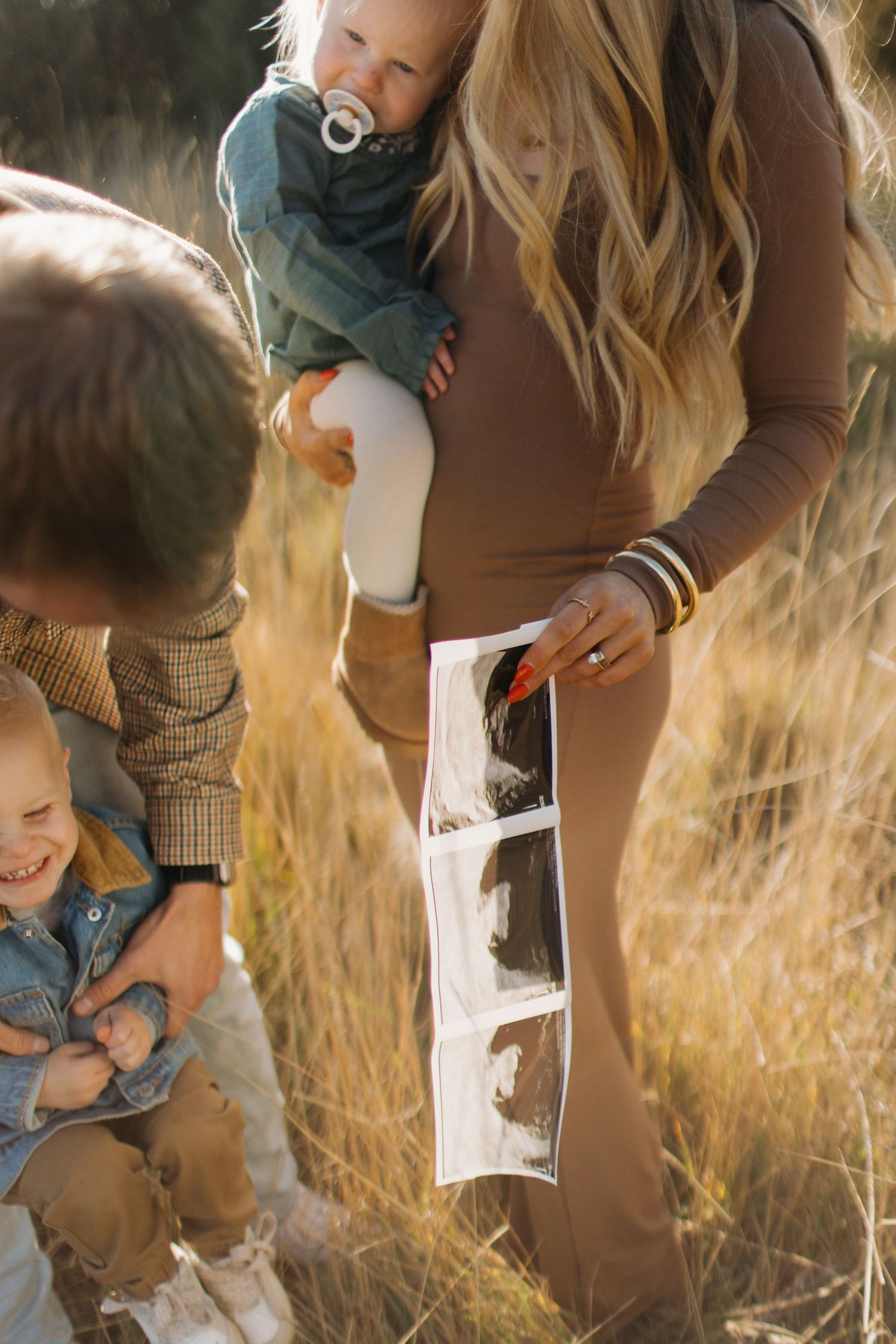Playful candid moments between parent and child in a sunlit field of golden grass.