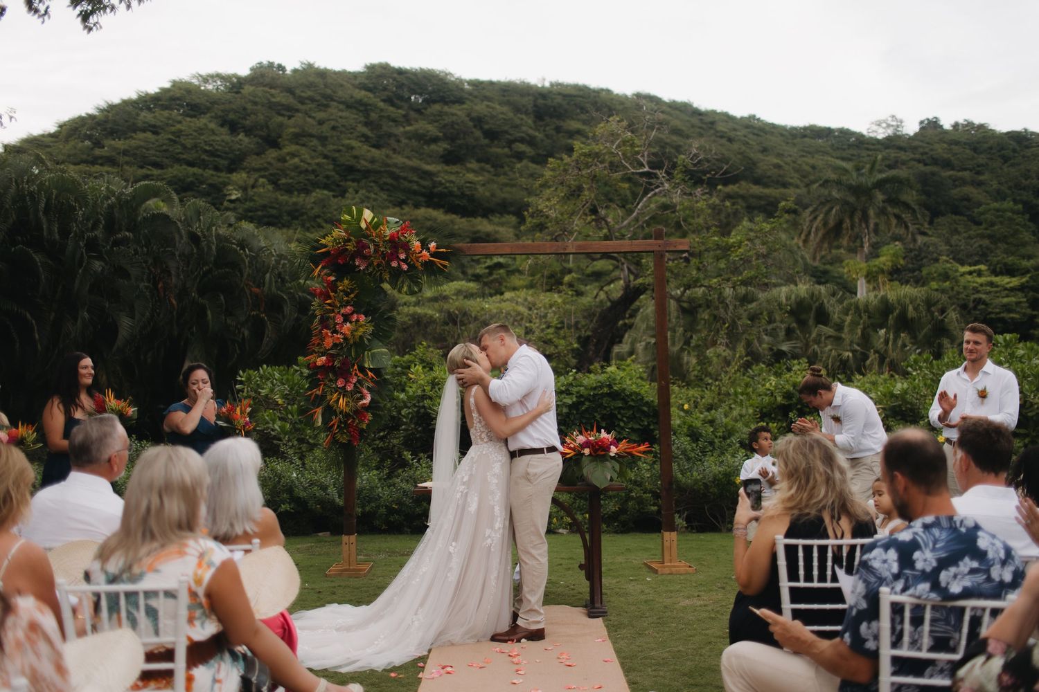 Outdoor garden wedding ceremony setup with tropical floral arrangements.