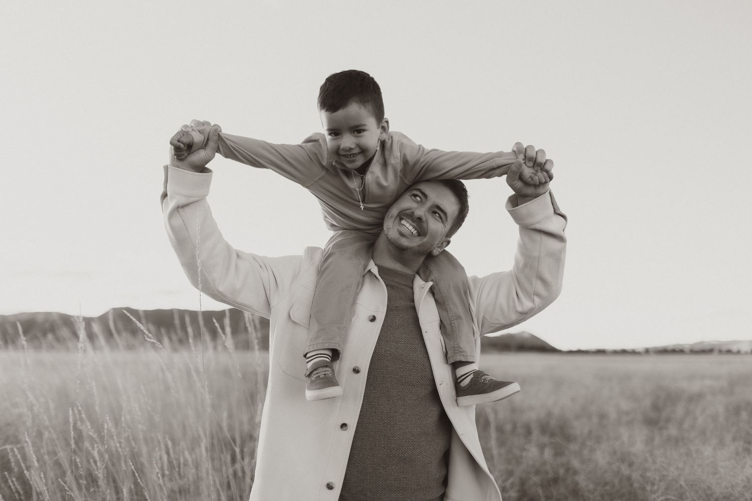 A heartwarming black and white portrait showing playful piggyback ride in a grassy field.