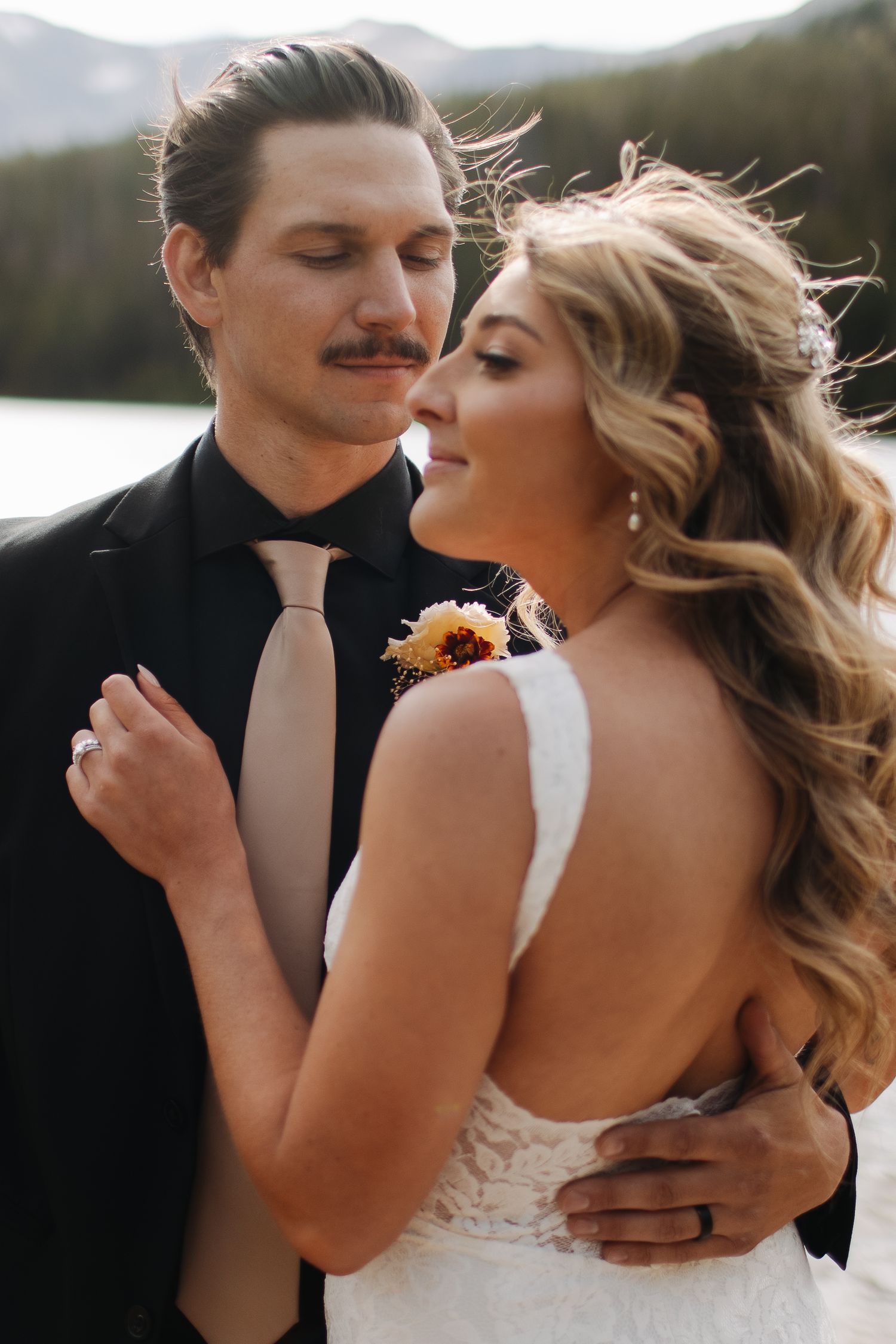 Intimate wedding portrait captured against mountain backdrop with dramatic lighting.