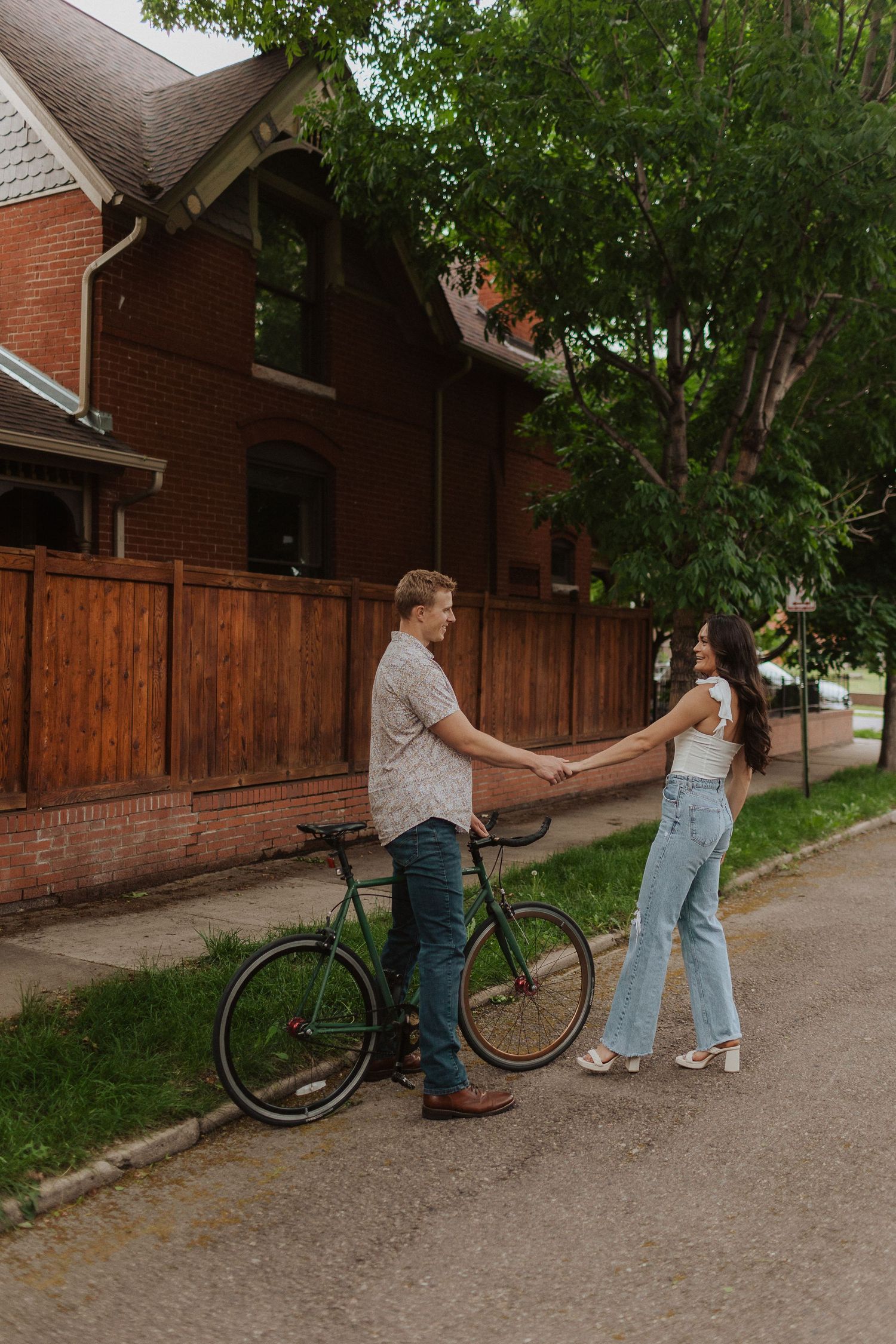 Playful sequence of couple interacting with vintage bicycle on tree-lined path.