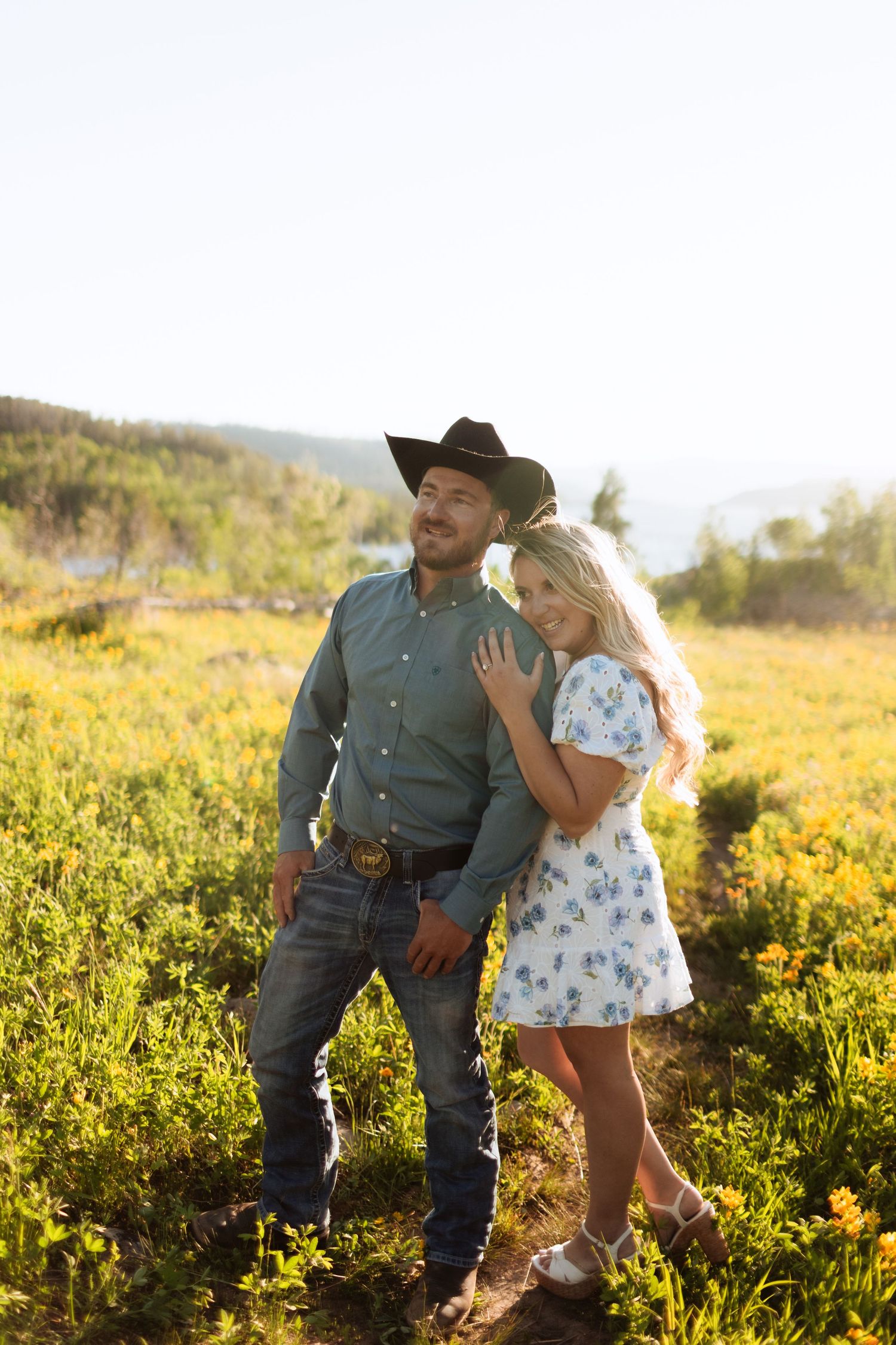Couple sharing romantic moments in a sunlit wildflower field at golden hour.