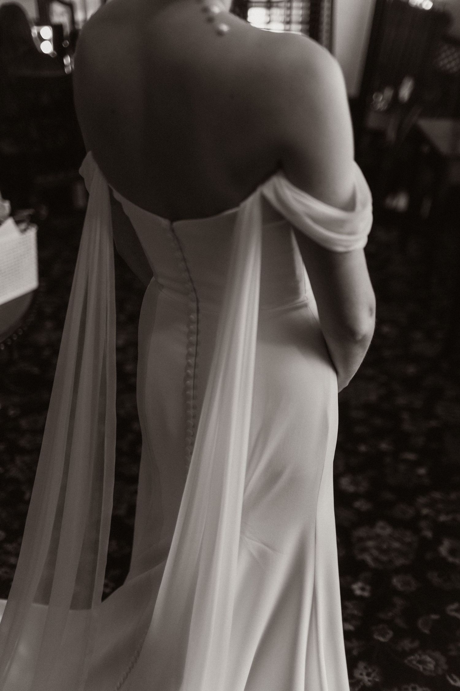 Close-up details of a classic white wedding dress with buttons and flowing fabric.
