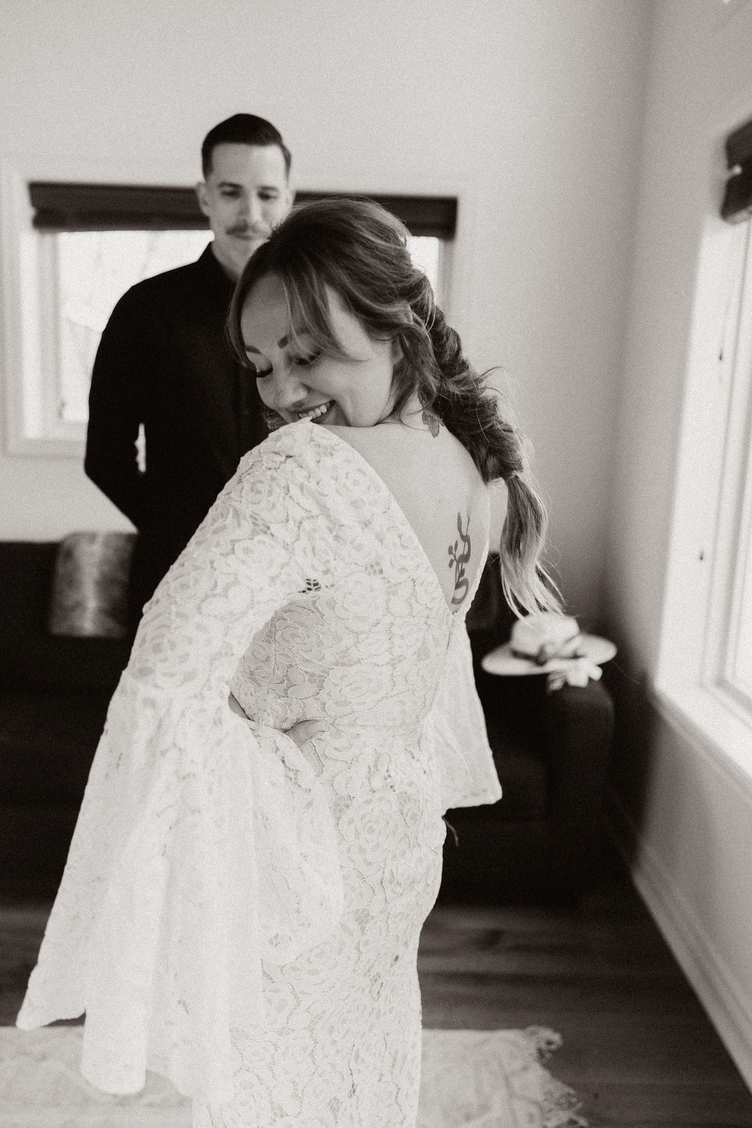 Black and white wedding photos showing close-up details of a lace wedding dress in natural window light.