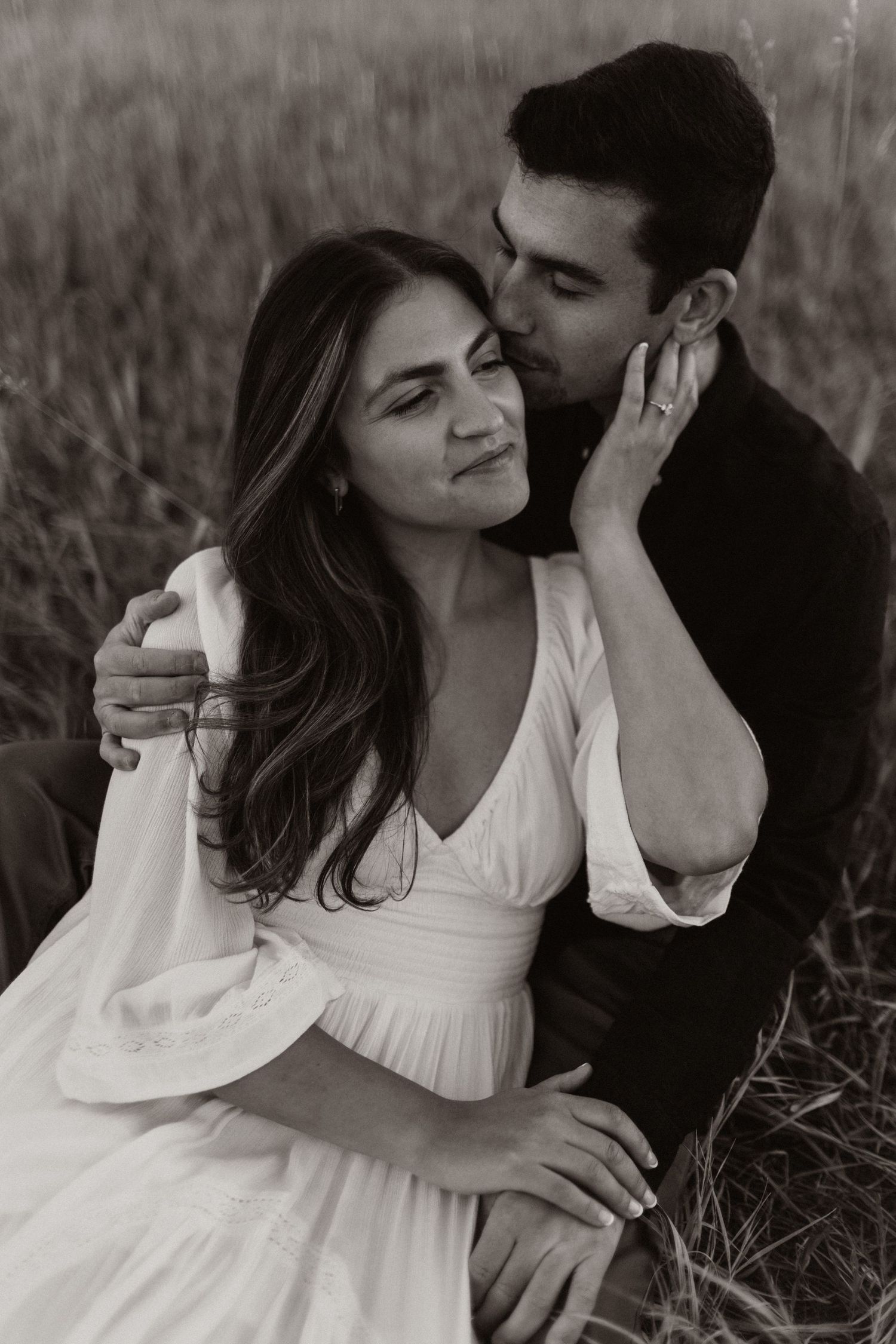 Intimate black and white portraits of couple embracing in tall grass.