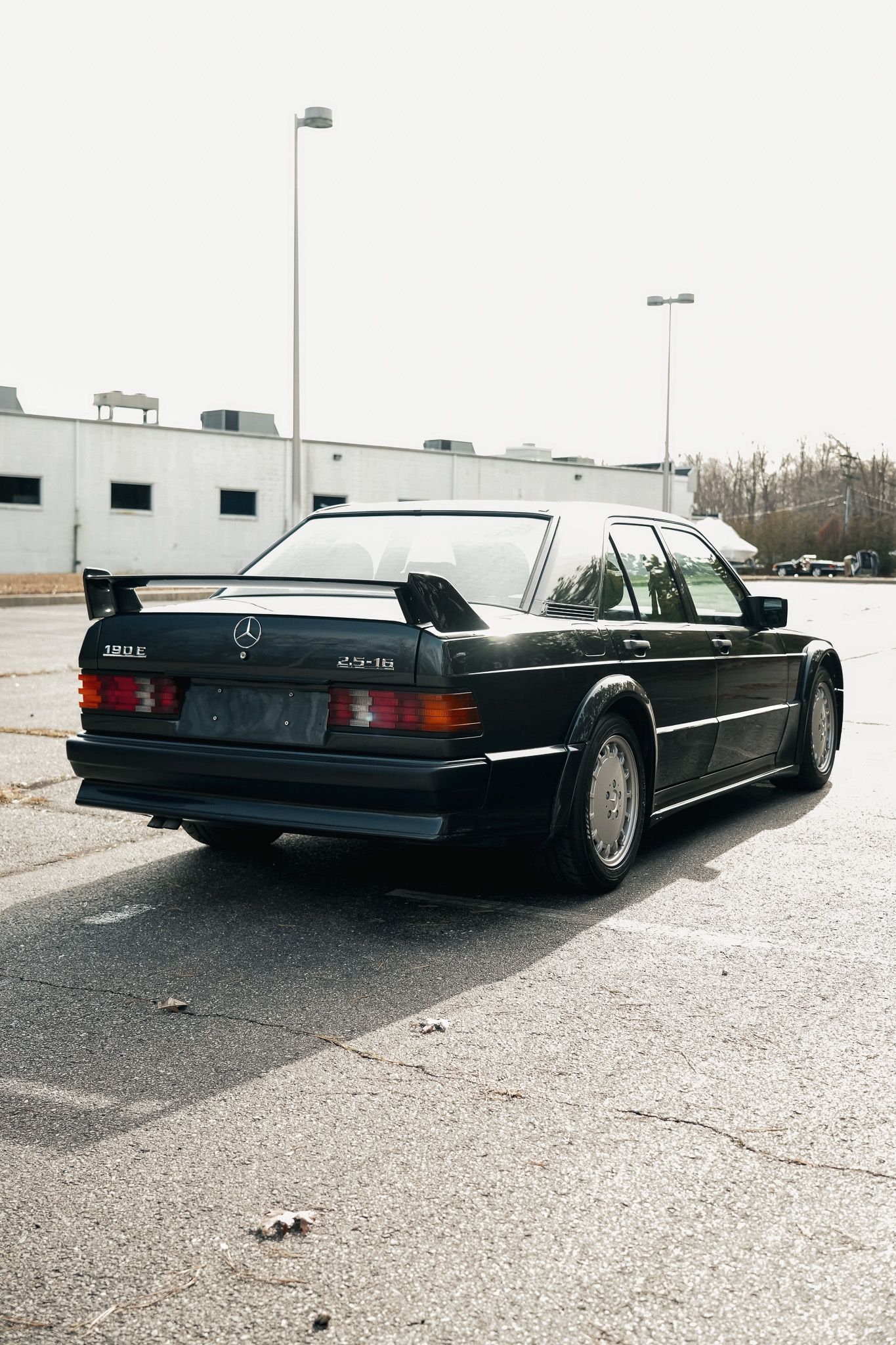 Black vintage Mercedes sedan photographed from rear quarter angle in parking lot.