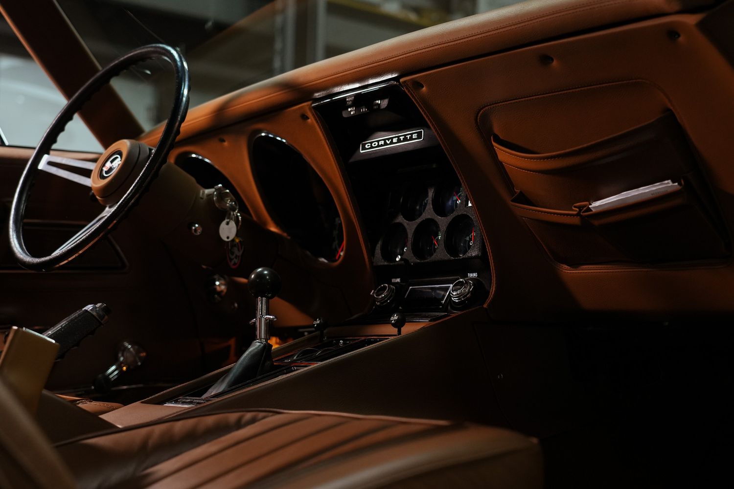 Interior view of vintage sports car showing brown leather dashboard and controls.