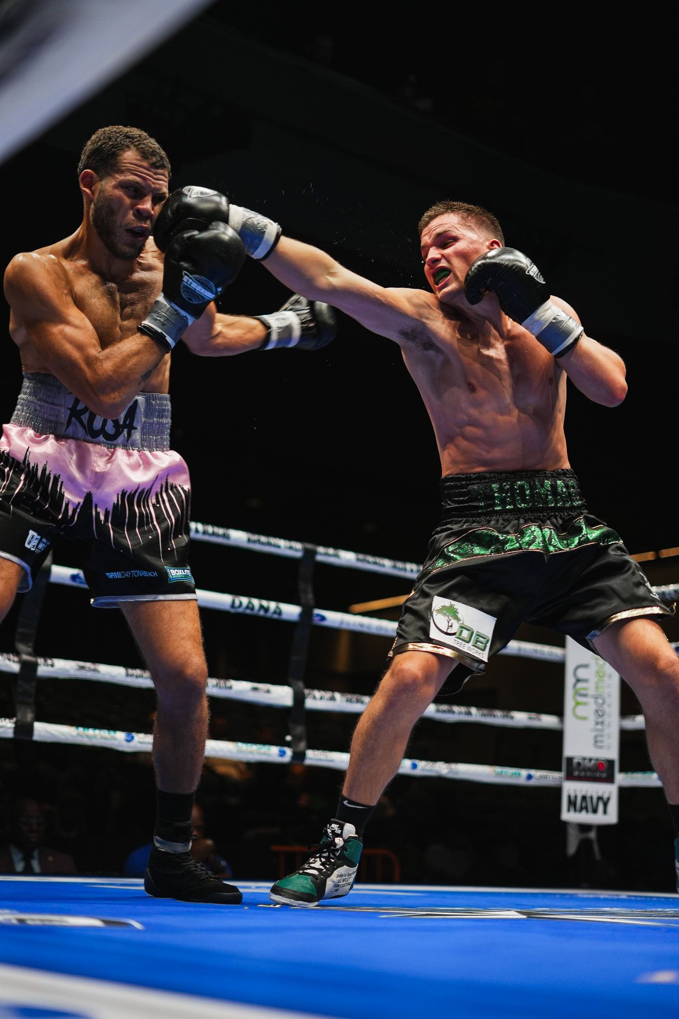 Two boxers exchange punches during an intense match in a professional boxing ring.