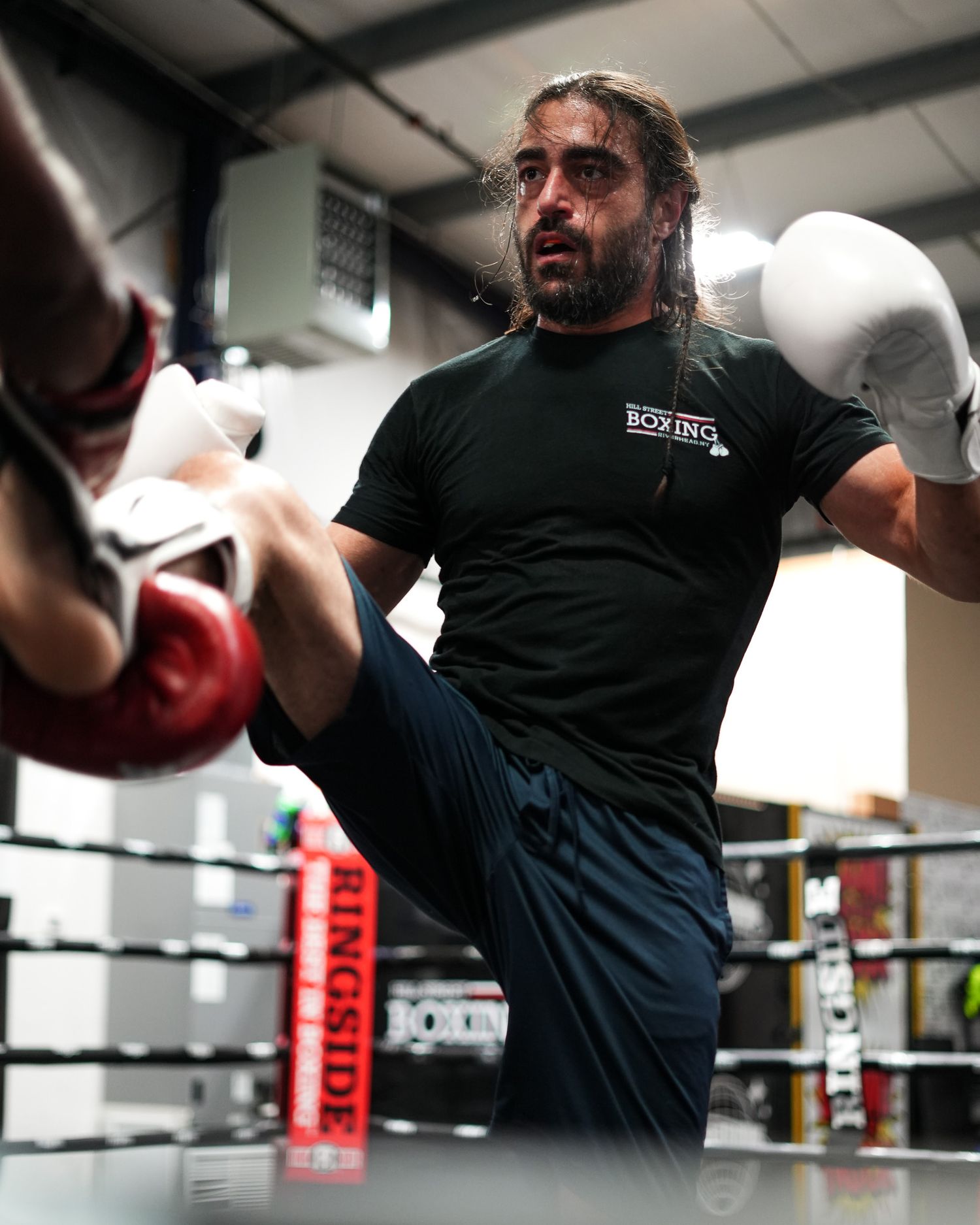 Side view of a boxer throwing a high kick during training.