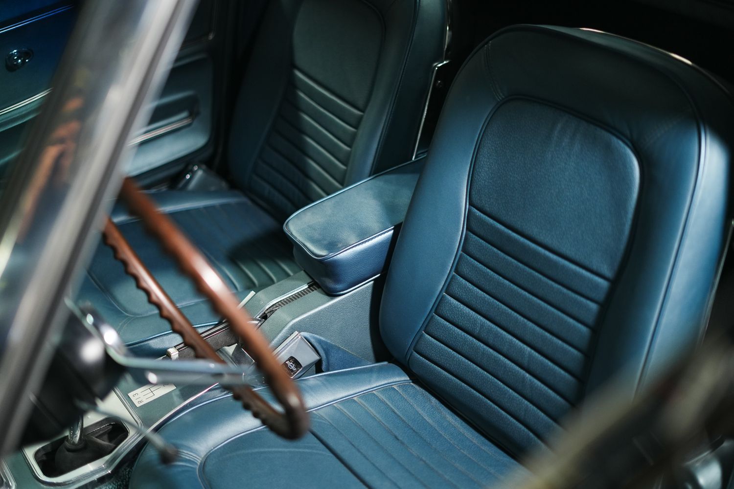 Classic car interior featuring black leather seats and wooden steering wheel.