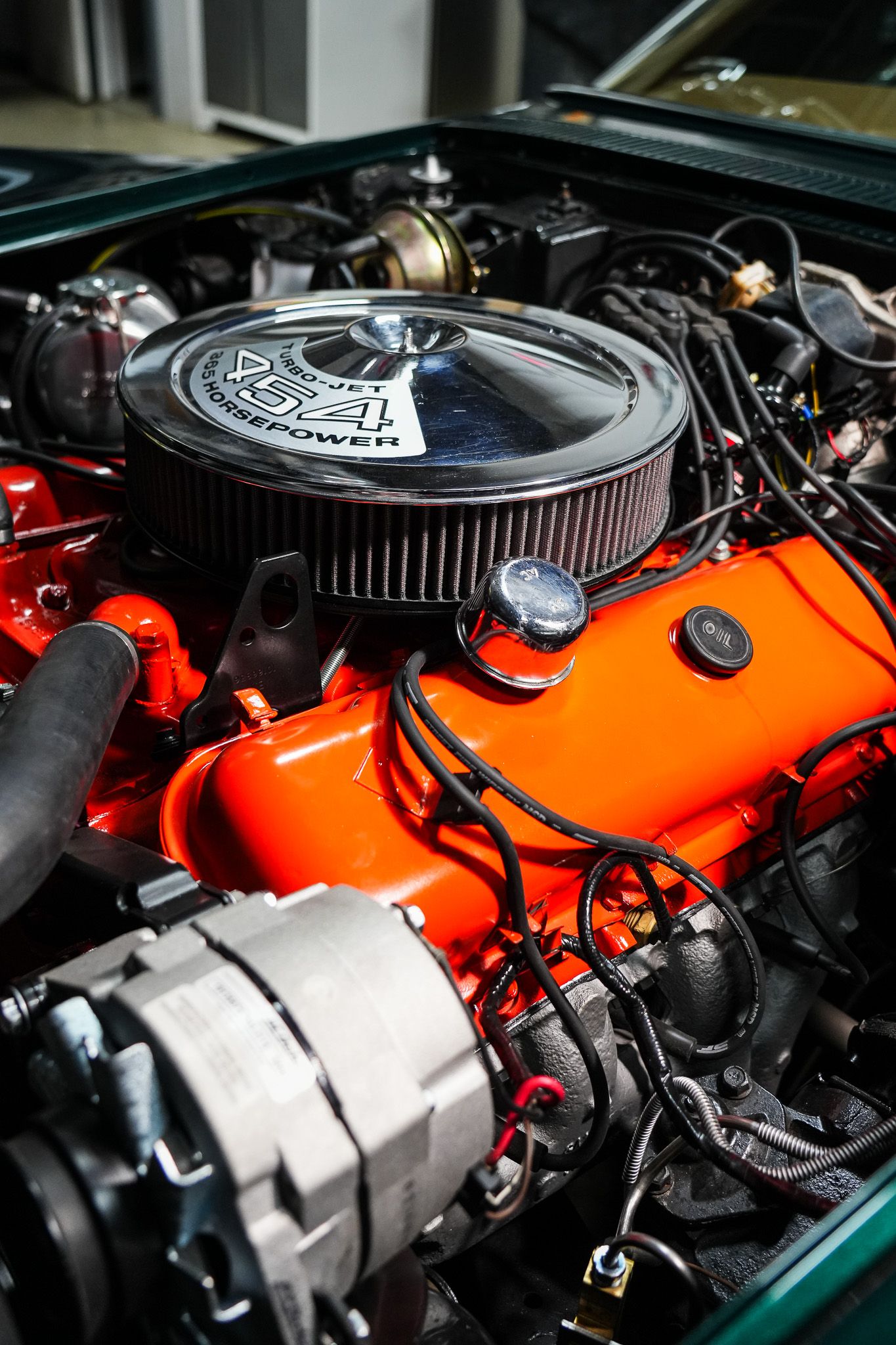 Orange painted high performance engine block with chrome air filter in classic car.