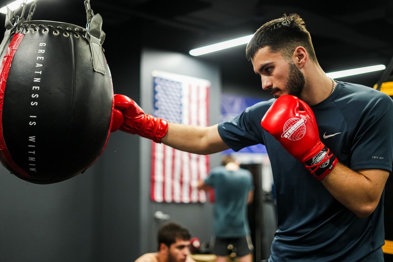 Boxer practicing punches on heavy bag in modern gym facility.