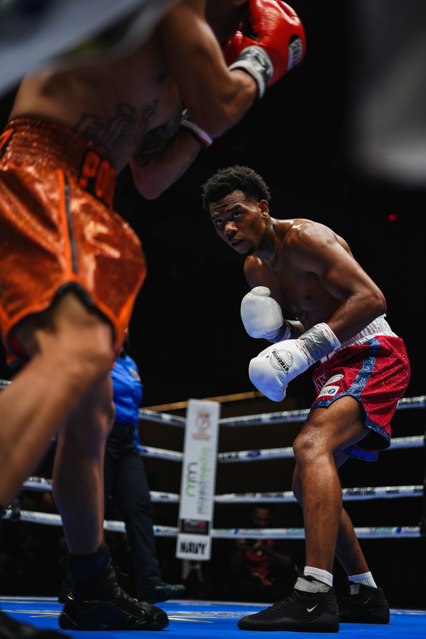 Boxers trade blows during a professional fight on a blue canvas ring.