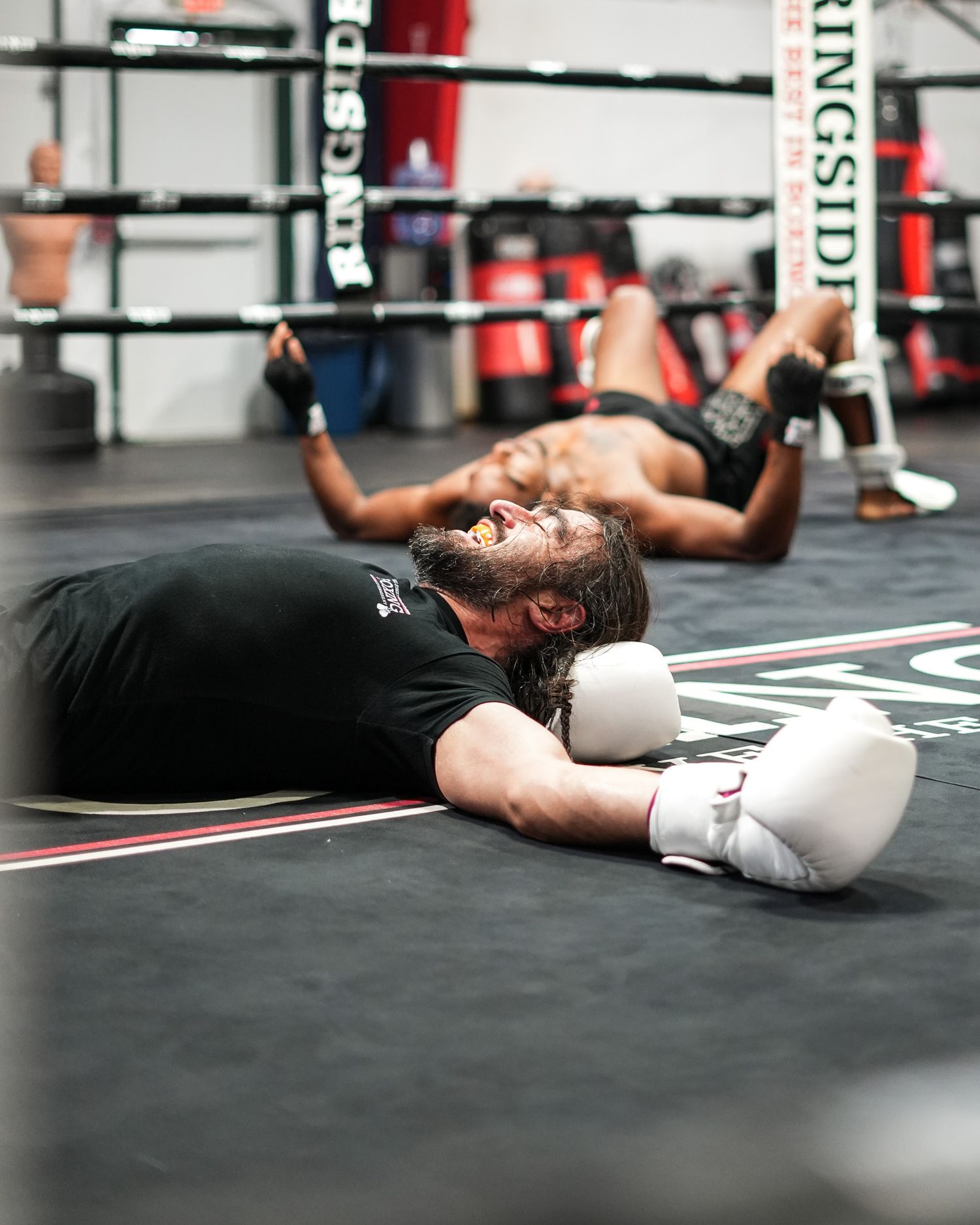 Exhausted boxer lying on boxing ring floor after intense workout.